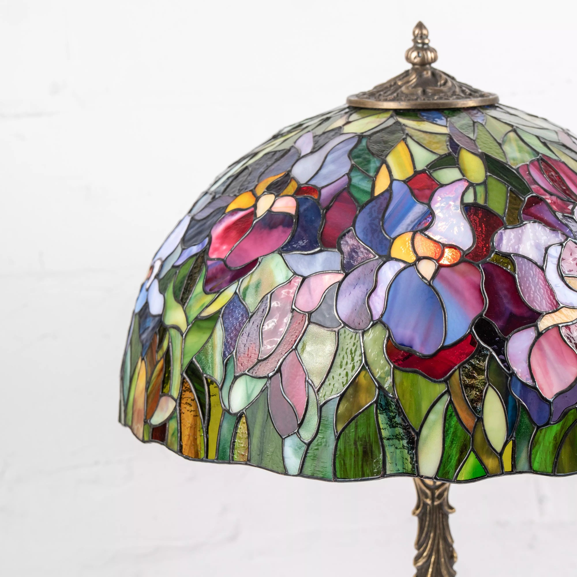 Close-up of stained glass lamp with multicolor iris flower petals and detailed glass textures