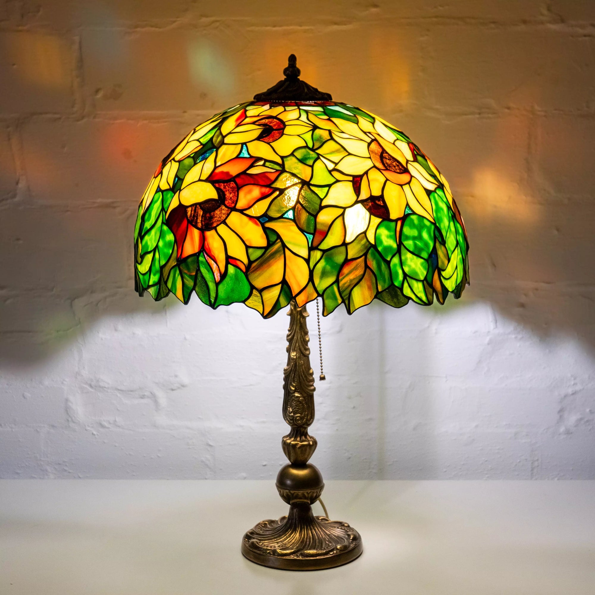 Illuminated sunflower stained glass lamp casting colorful reflections on wall