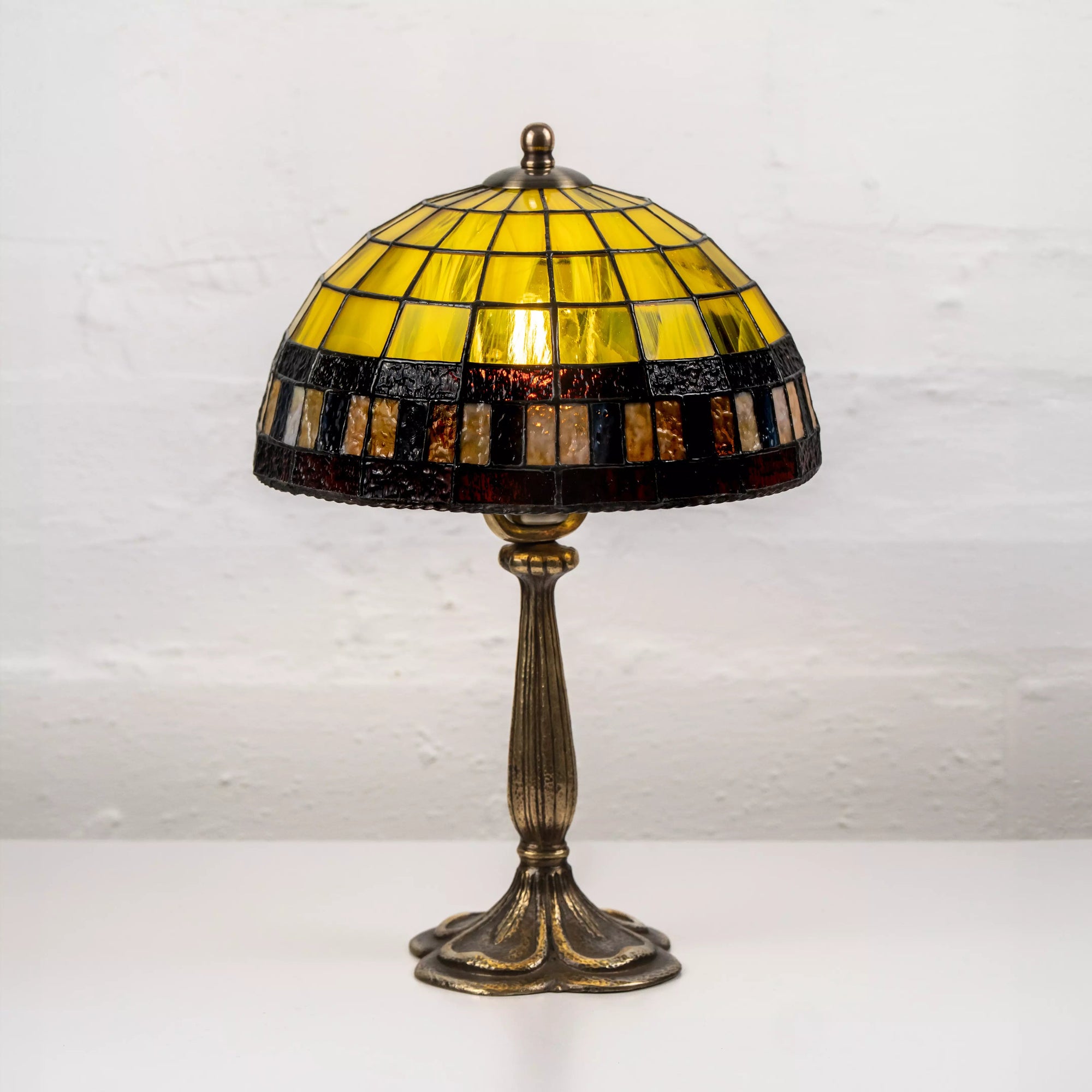 Yellow stained glass lamp on ornate bronze-tone stand, displayed against white background