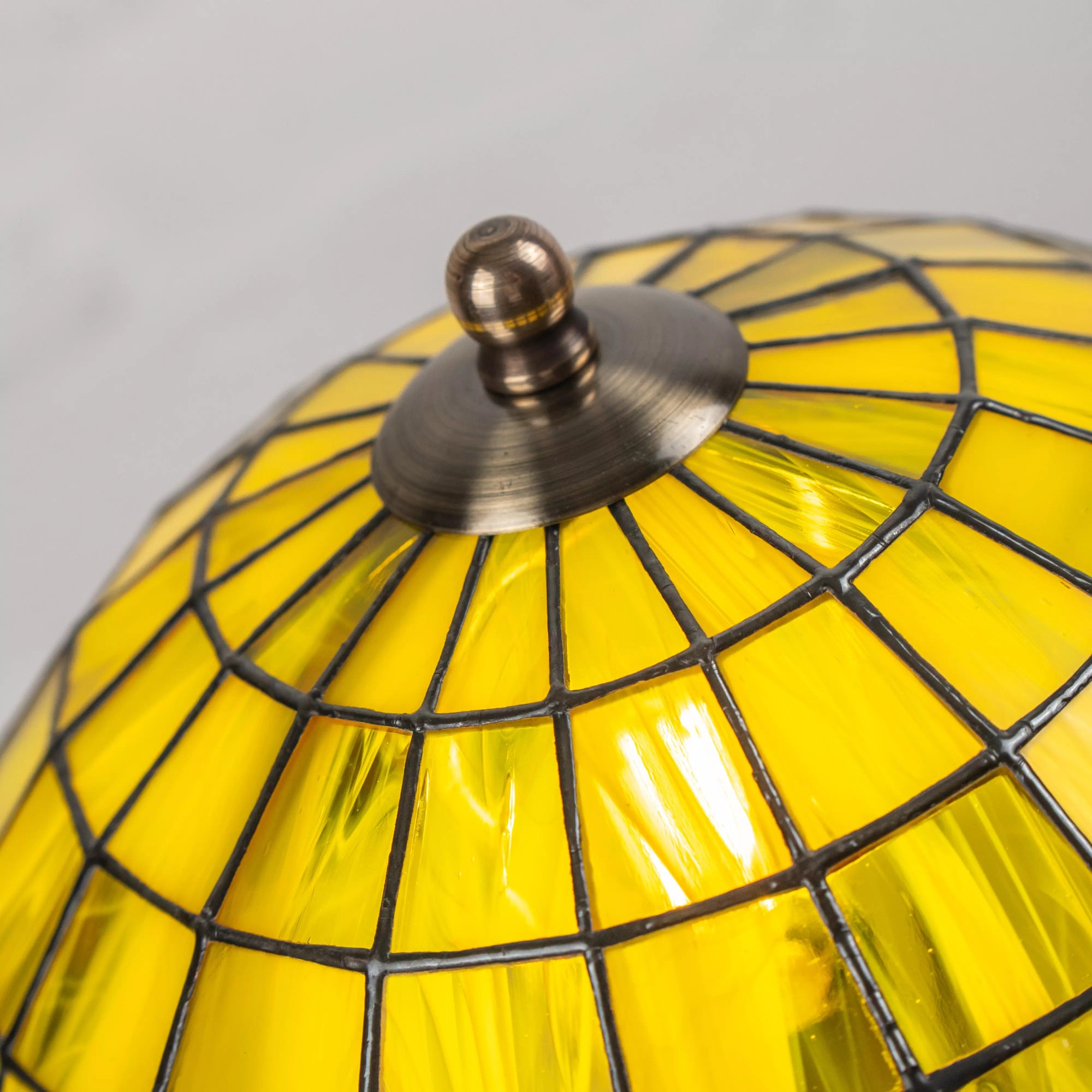 View from above of stained yellow glass dome with central bronze cap and tile pattern