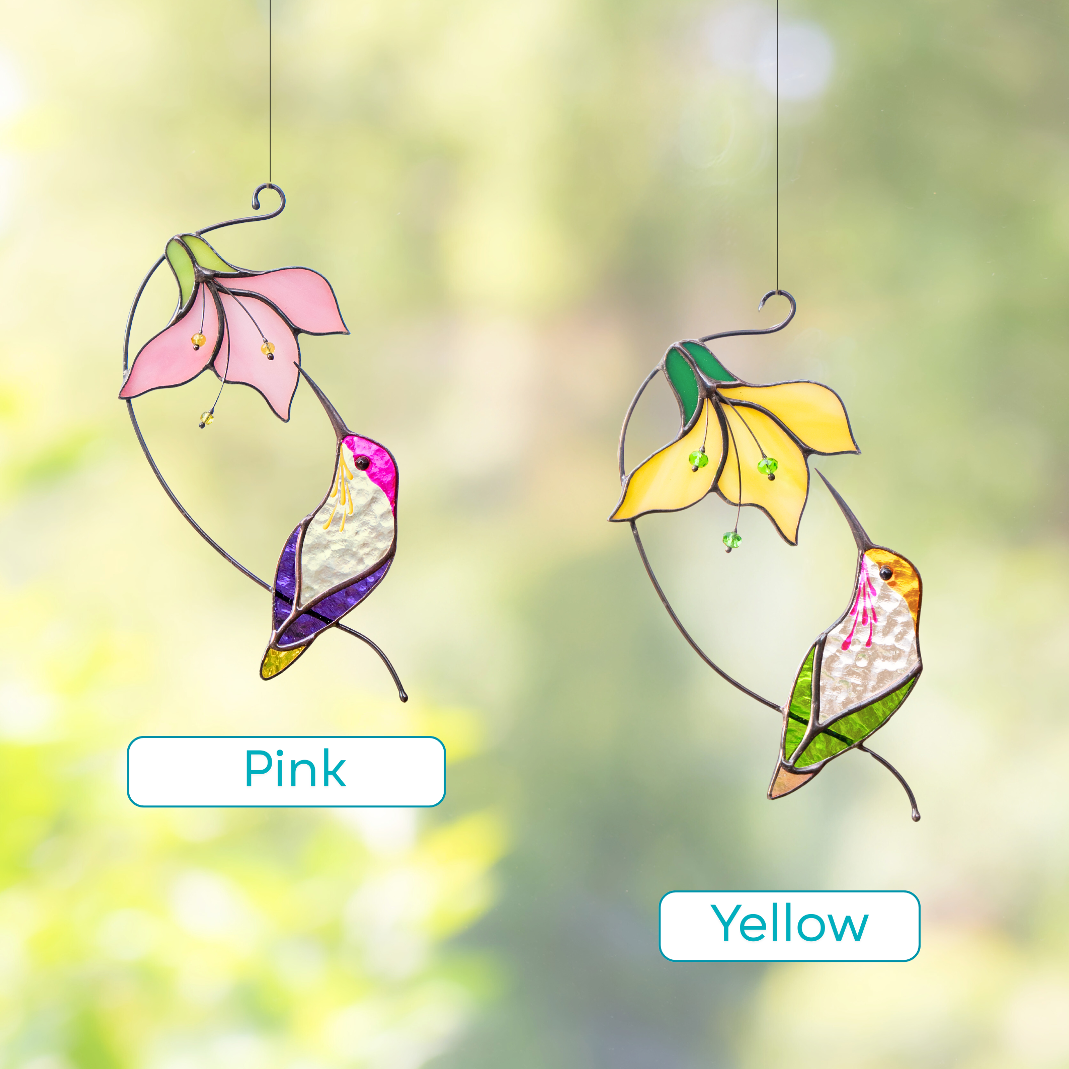 Two stained glass suncatchers hanging in the window: one hummingbird with a pink flower and one with a yellow flower