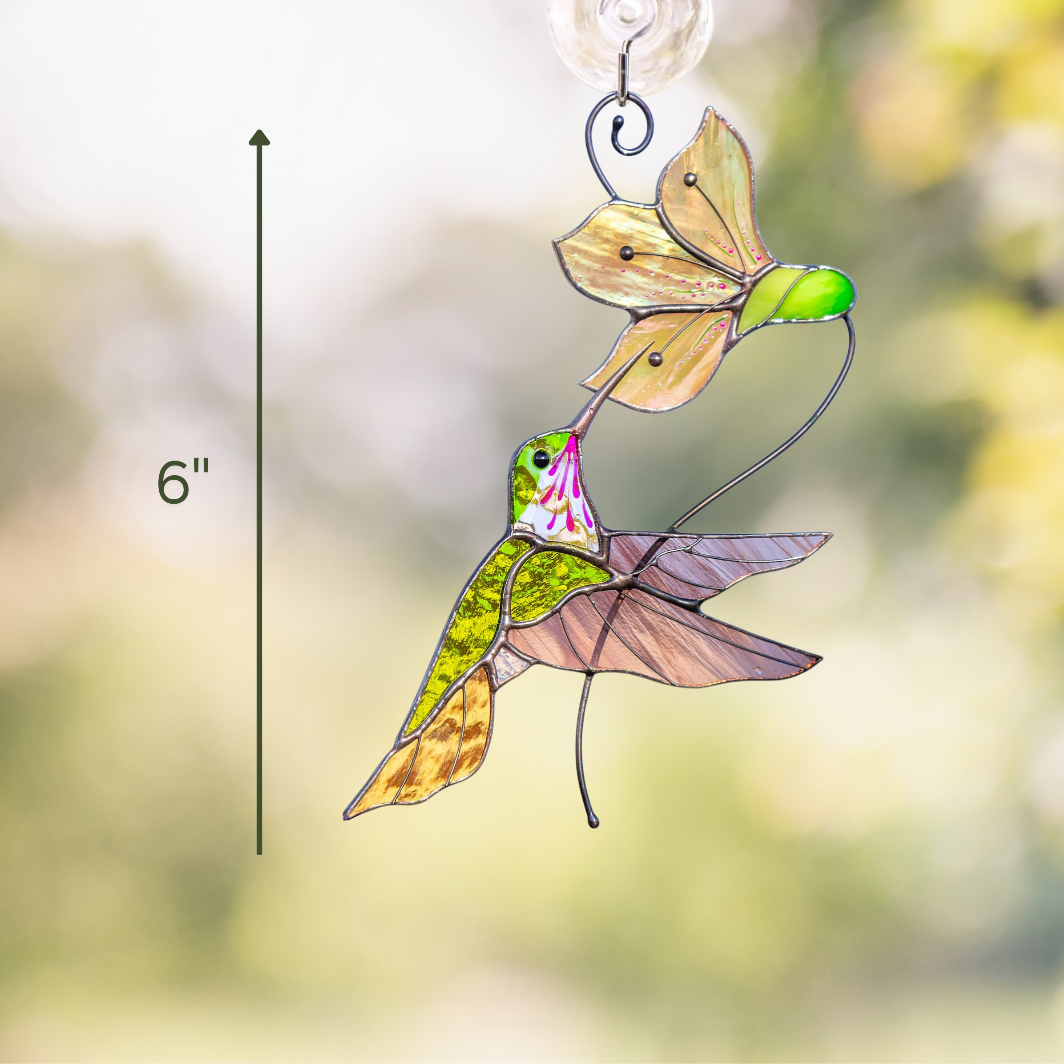 Close-up of window-hung suncatcher showing green hummingbird with pink-white flower and arrow at 6"