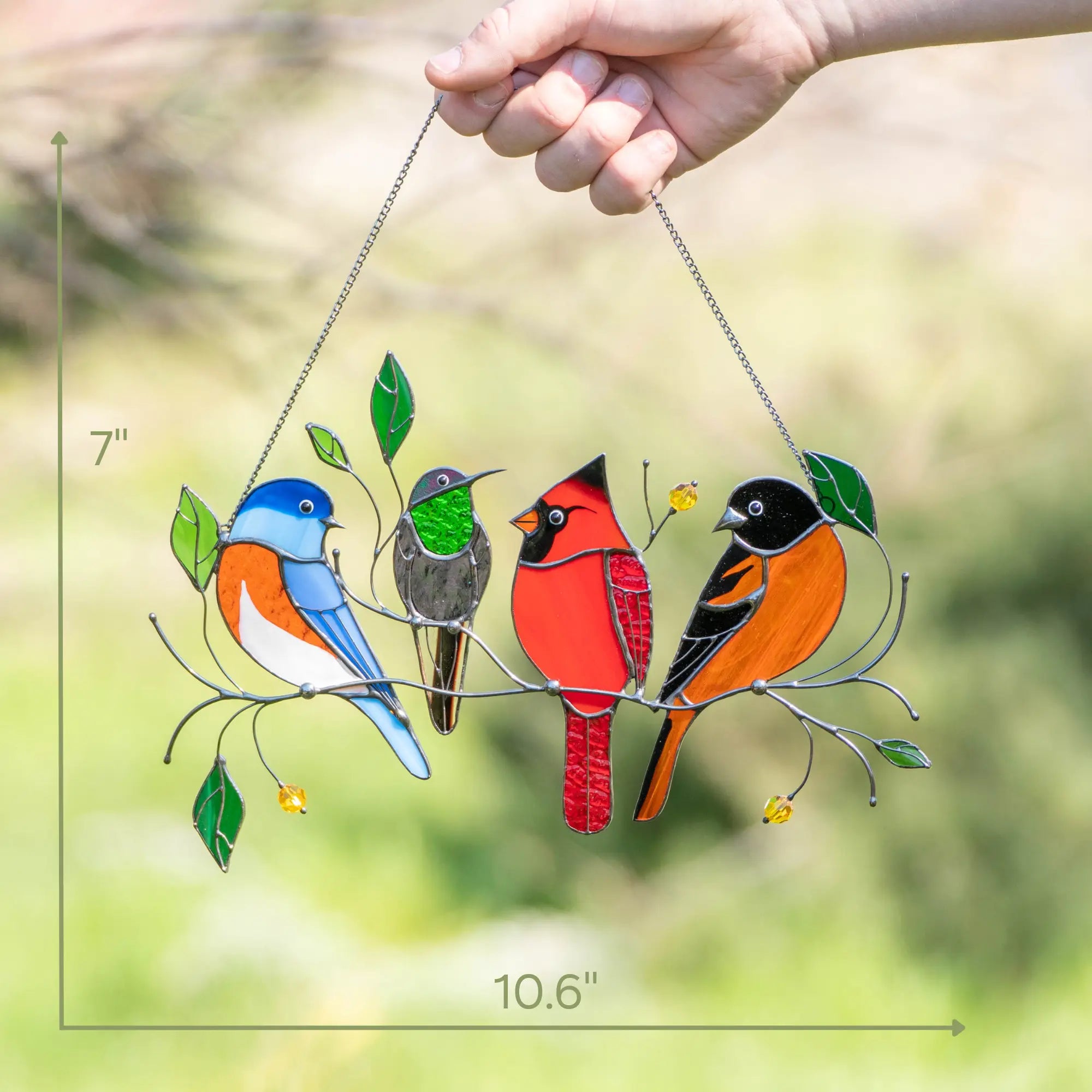 Hand holding stained glass piece with bluebird, hummingbird, cardinal, and oriole, size dimensions shown.