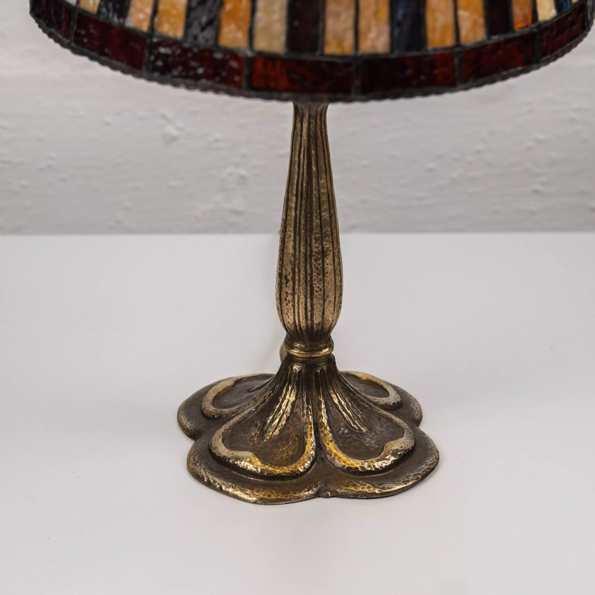 Close-up of metal lamp base with vertical ridges and antique-style bronze-gold patina