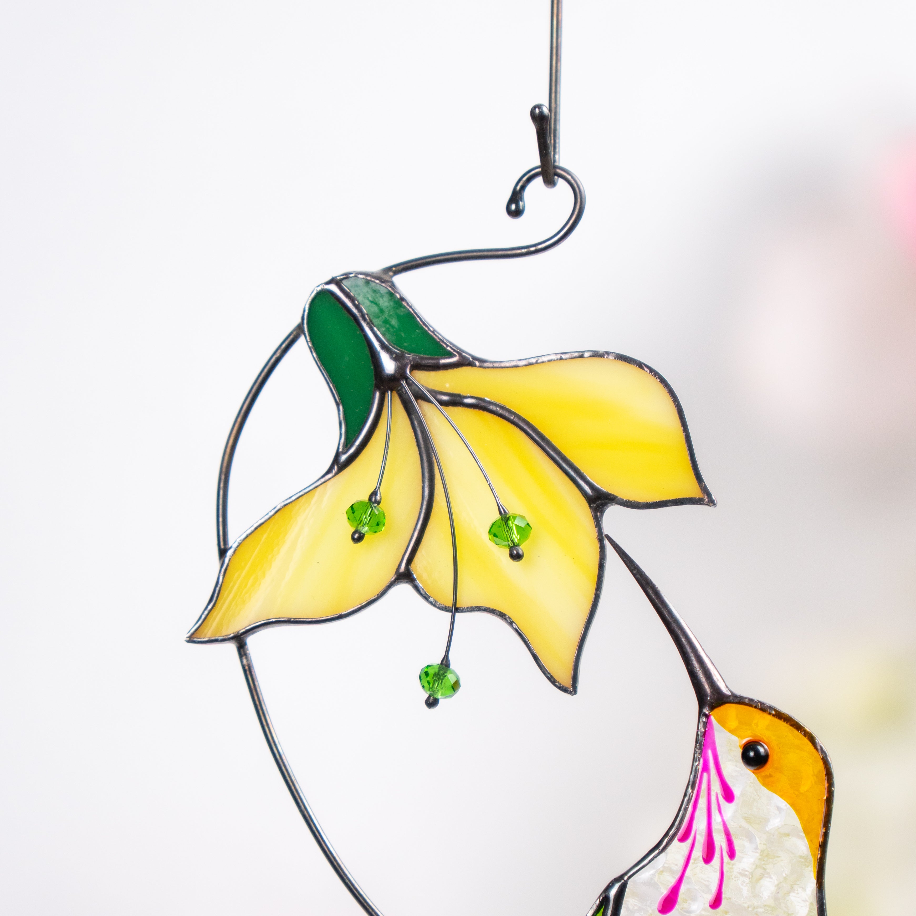 Detailed view of yellow flower with three green beaded stamens from a stained glass suncatcher.