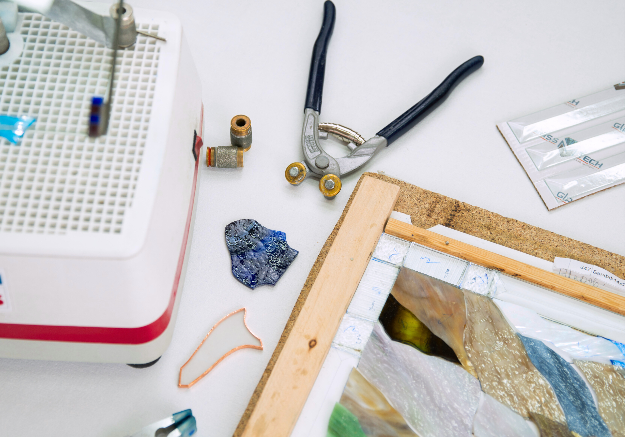 Tools and materials for stained glass art on a white workspace