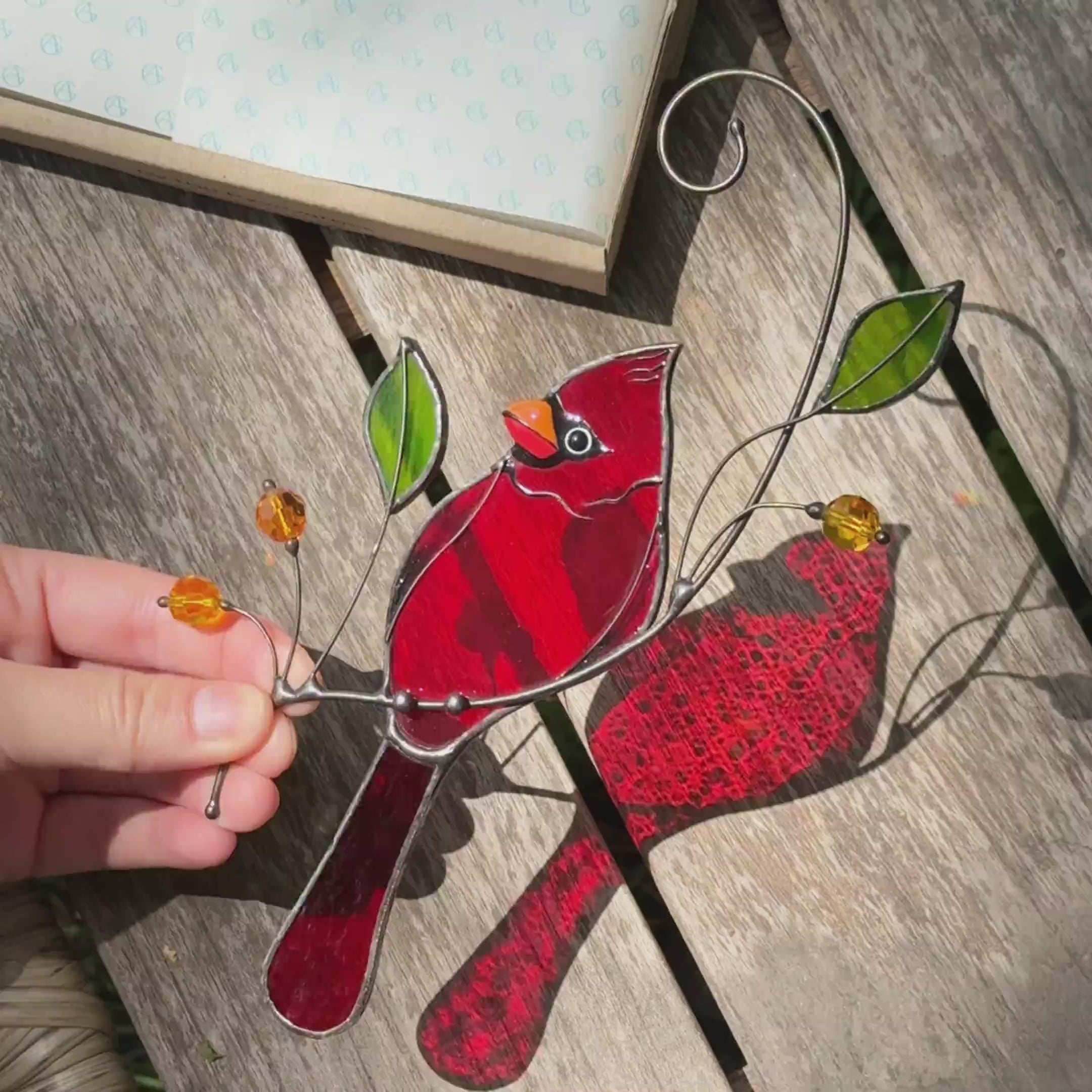 Stained glass cardinal perched on a branch with green glass leaves suncatcher