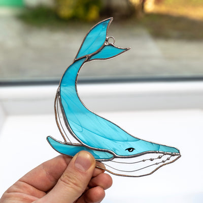 Suncatcher of a stained glass light blue whale window hanging