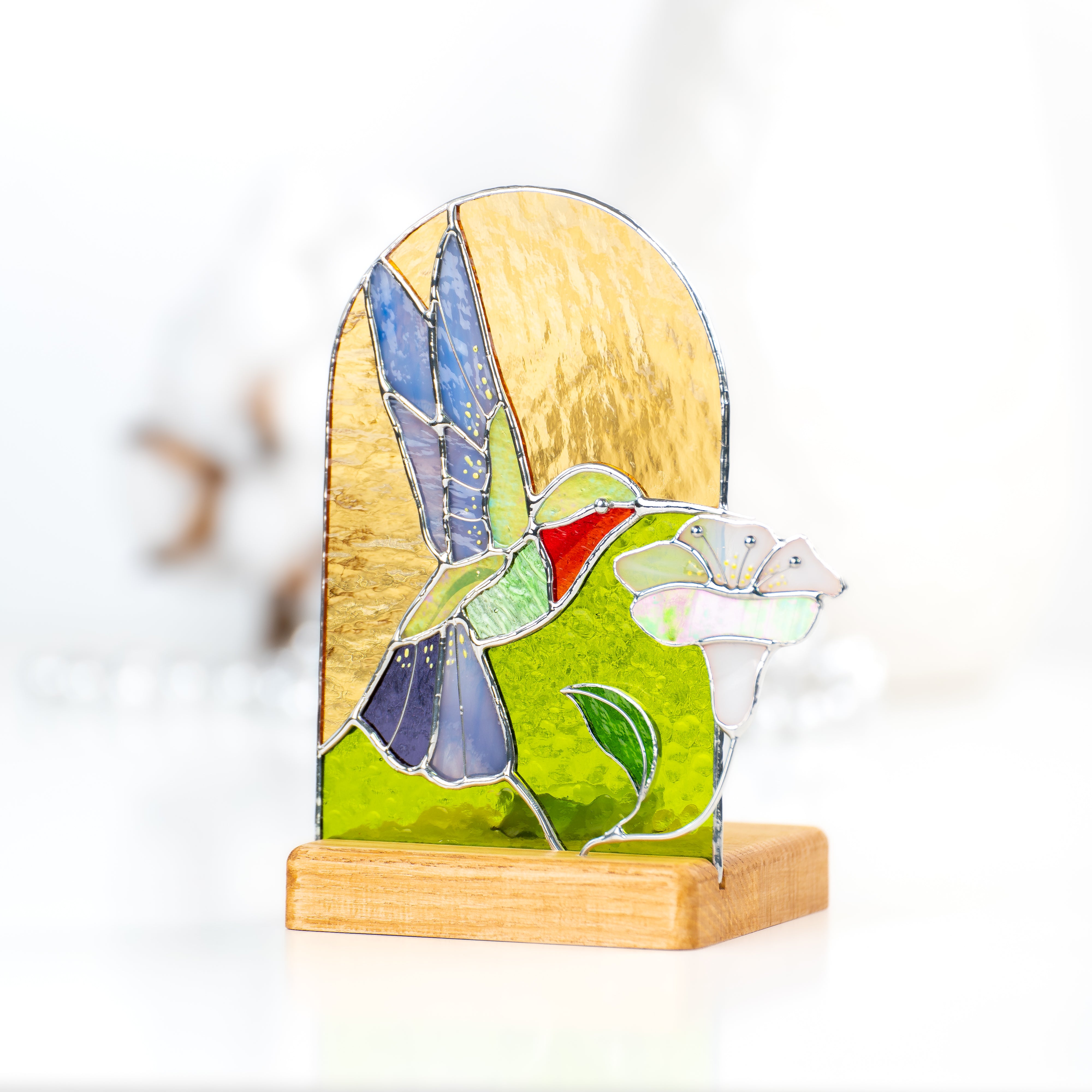 Candle-lit panel in a wooden base depicting a flying hummingbird and the flower of stained glass