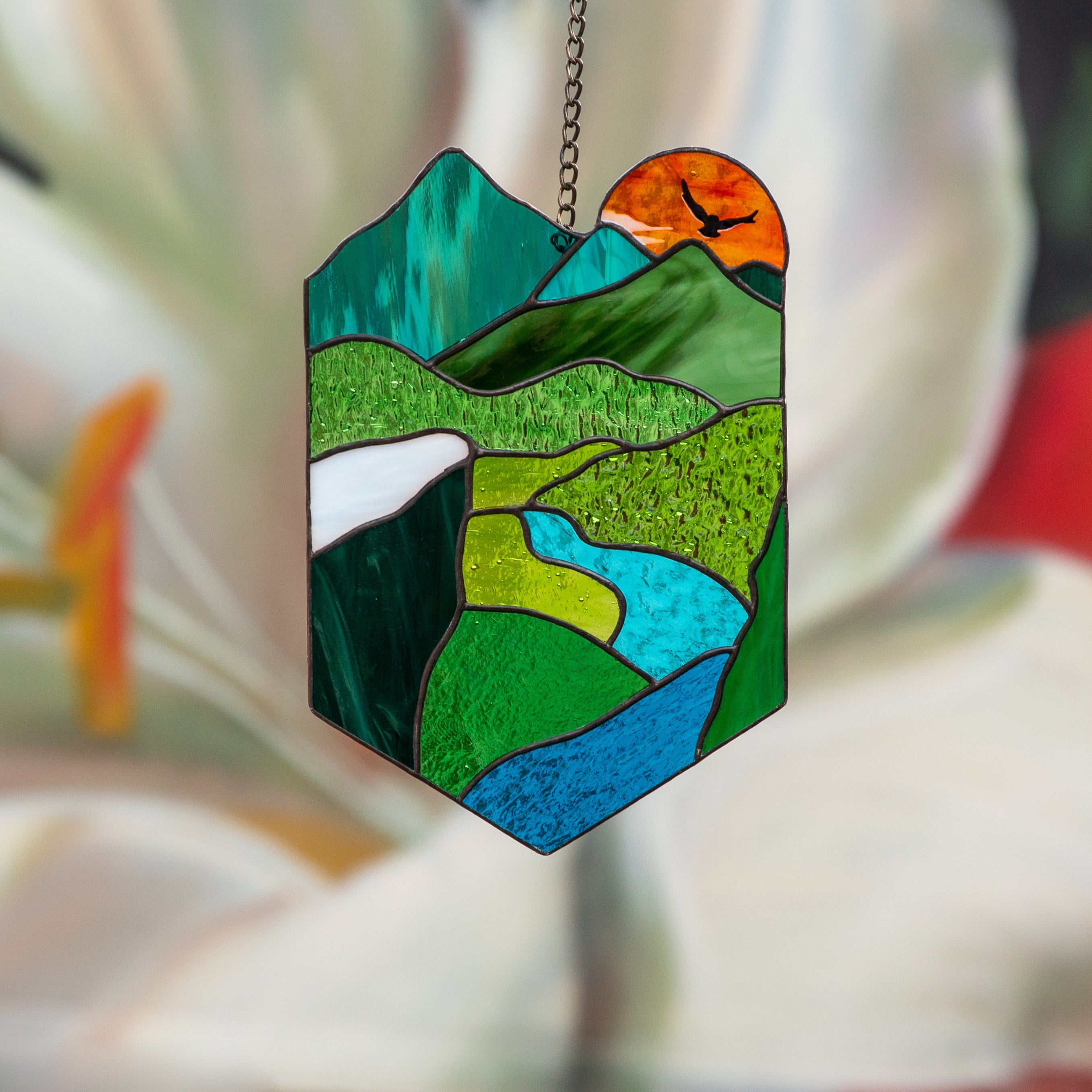 Bright stained glass panel depicting nature and the orange sun