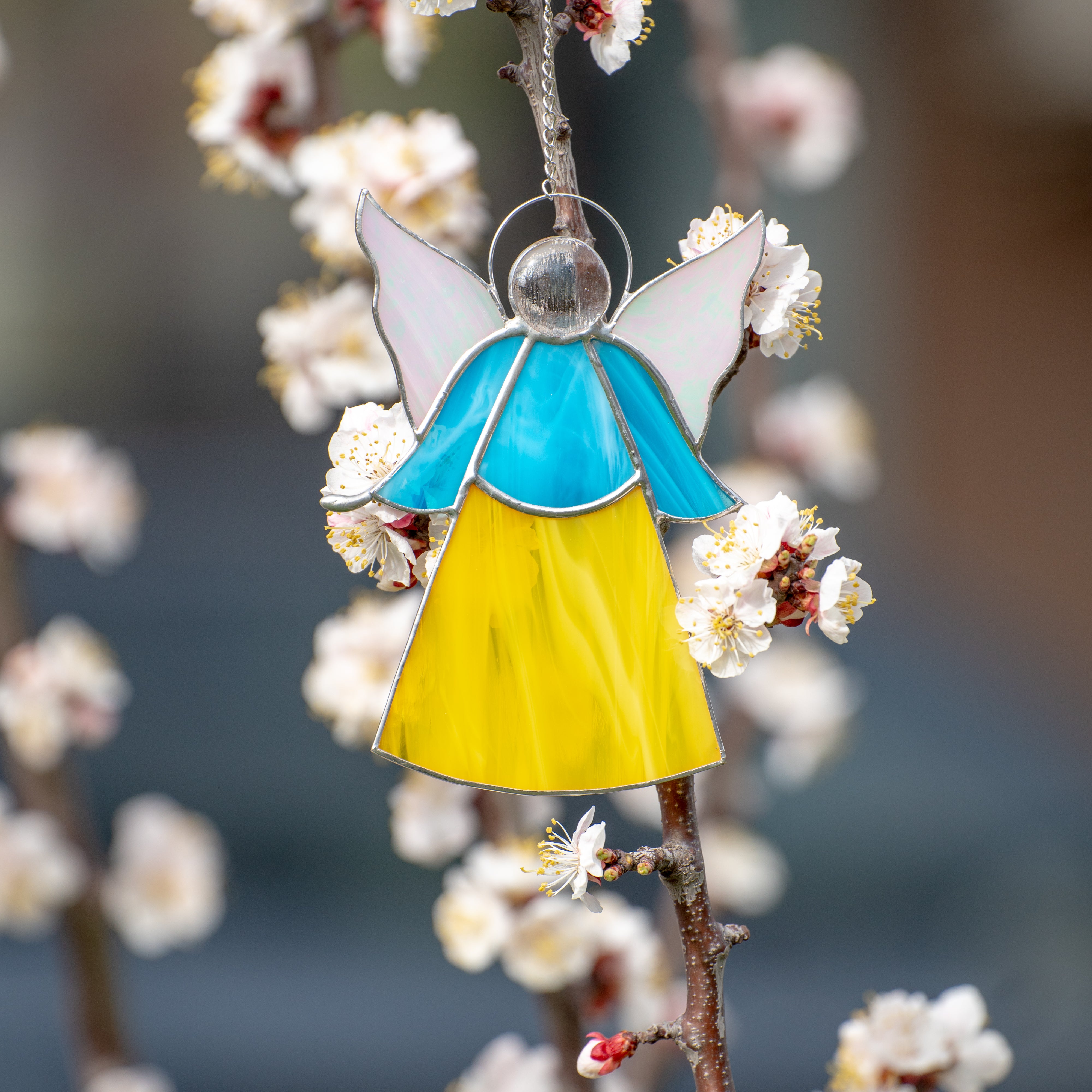 Stained glass window hanging of a blue above and yellow below angel