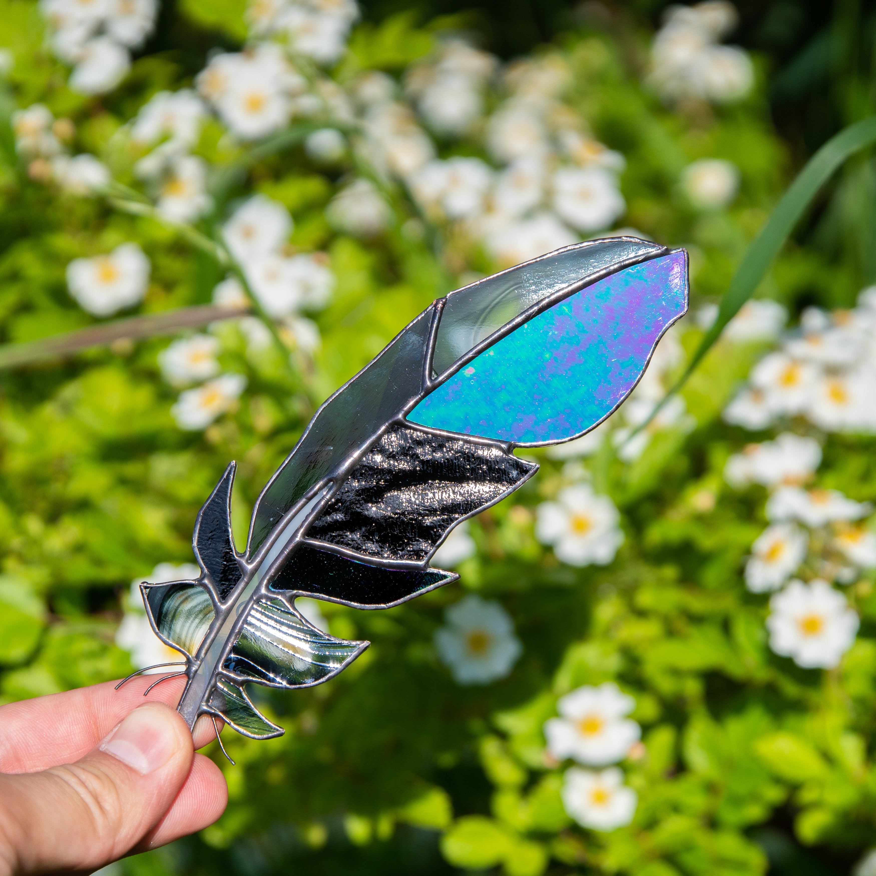 Stained glass window hanging of raven feather with modulating parts