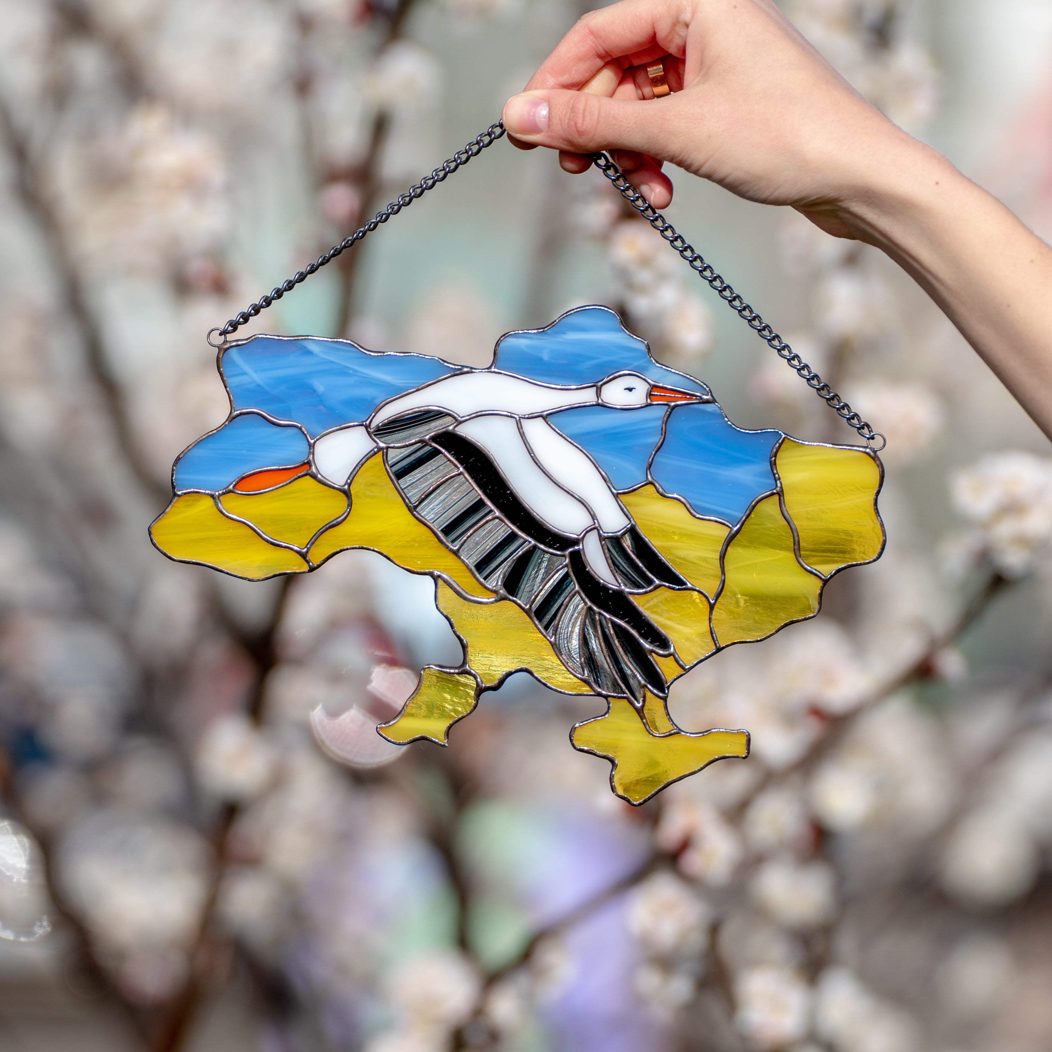 Stained glass window panel in the shape of Ukraine with the flying stork in the middle