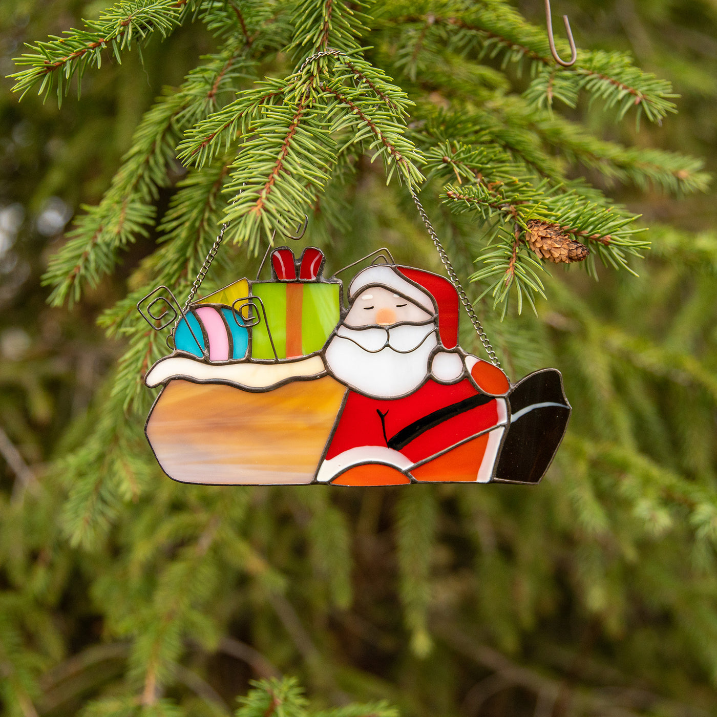 Stained glass Santa lying next to the gifts suncatcher used as a new year tree decoration