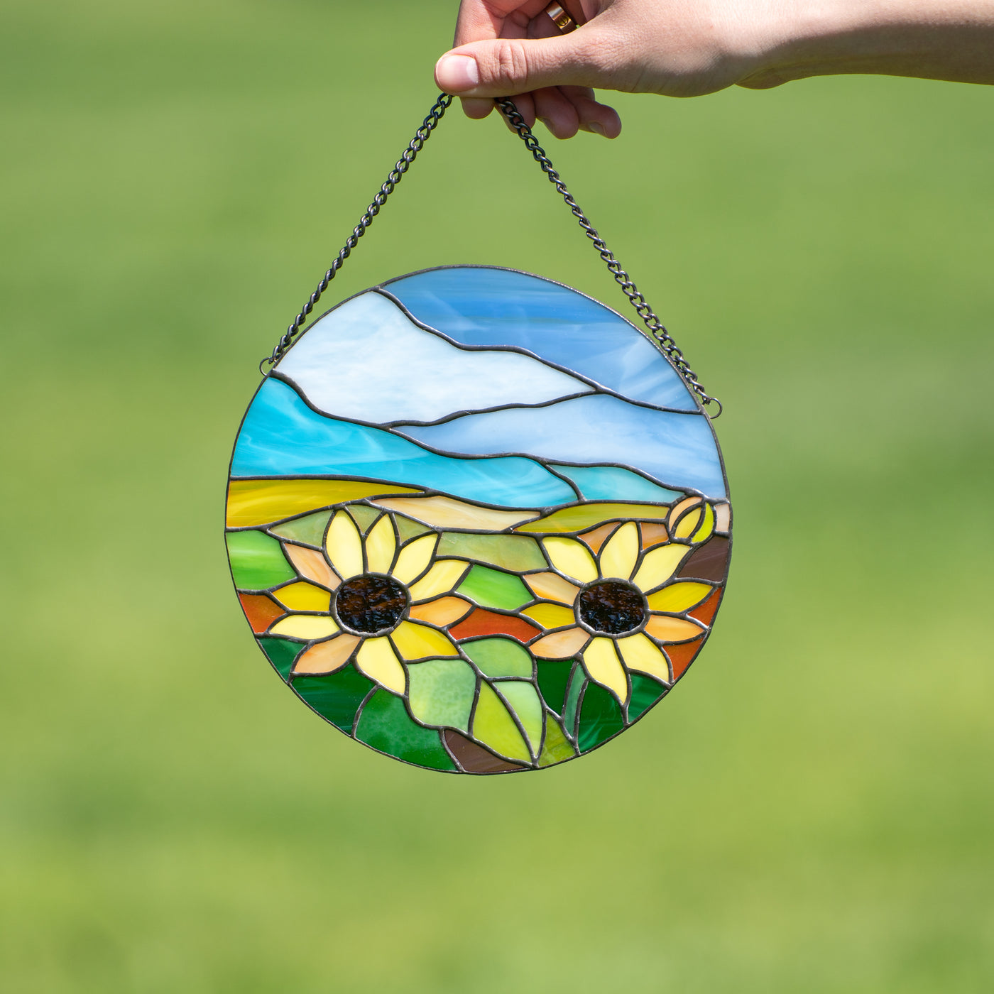 Stained glass window hanging depicting sunflowers and blue skies