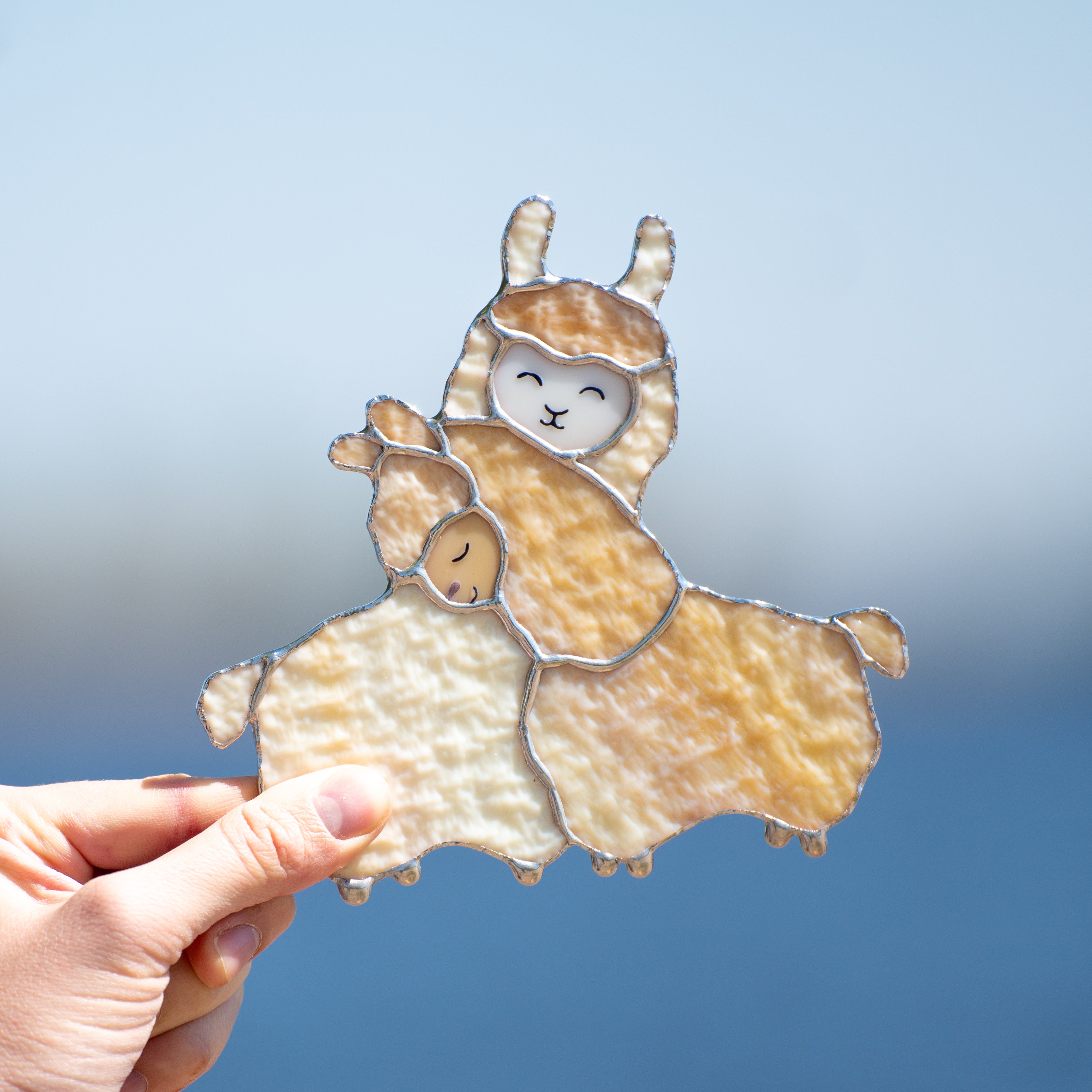 Two llamas cuddling window hanging of stained glass