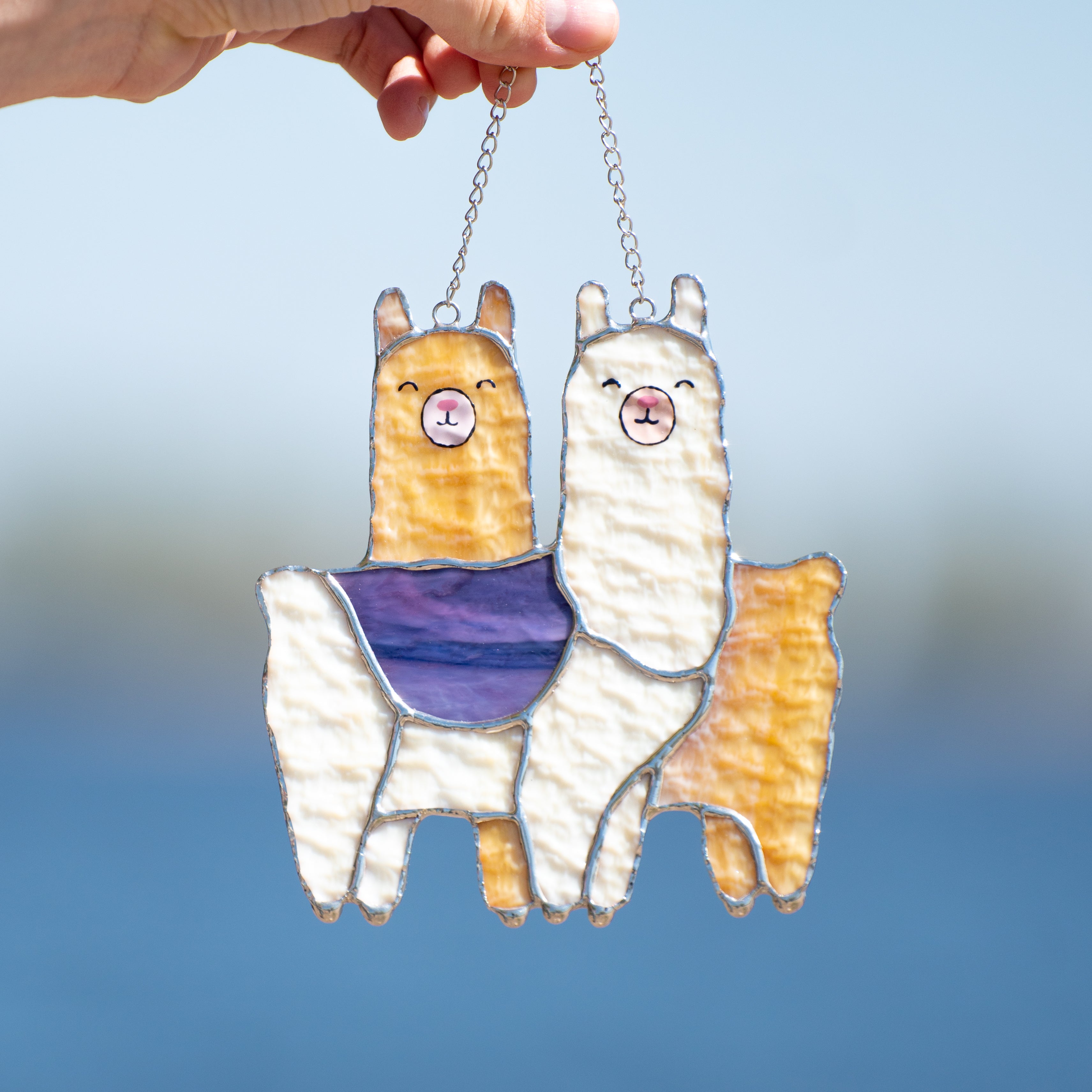 Stained glass window hanging of two llamas standing across each other