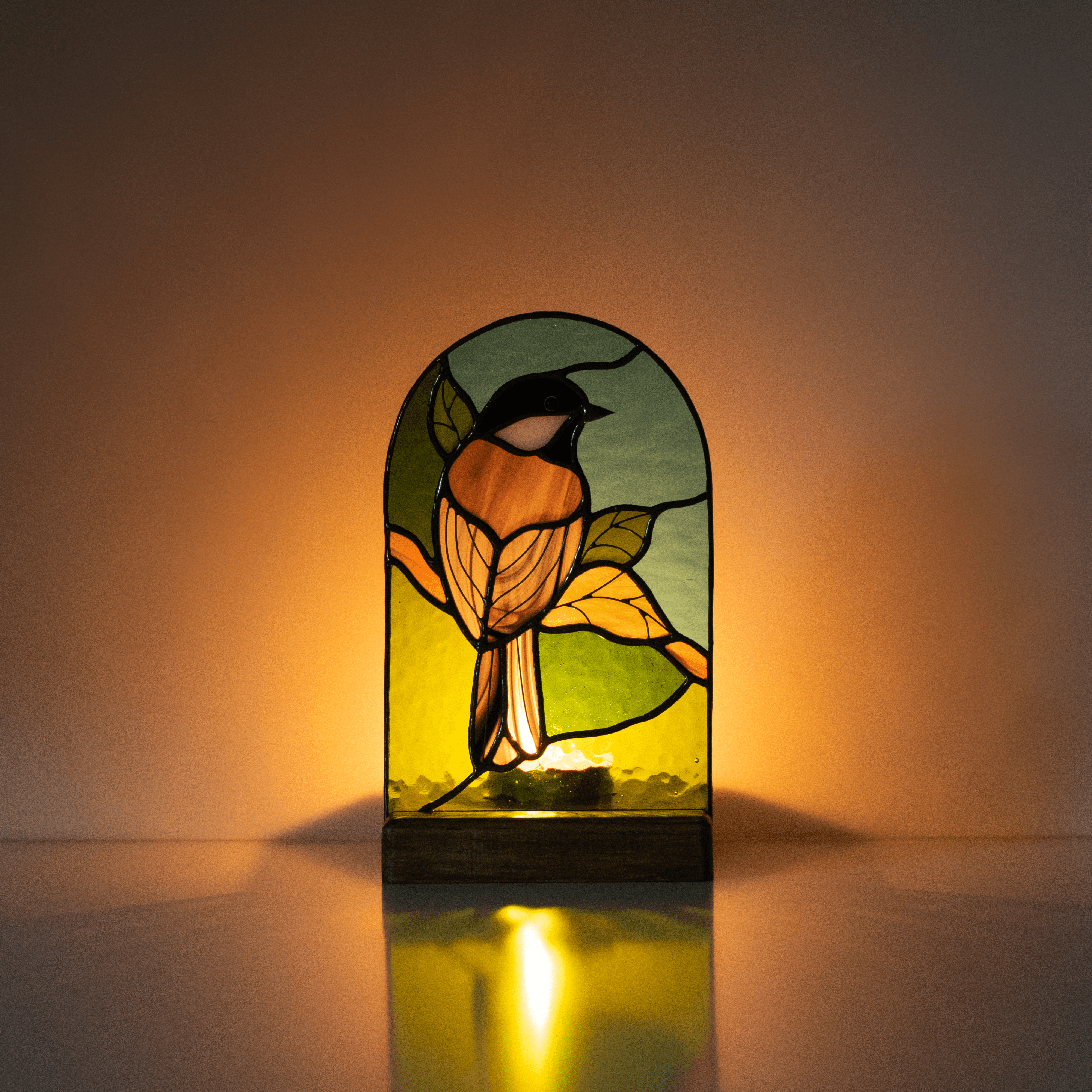 Lit with the candle stained glass panel depicting a chickadee