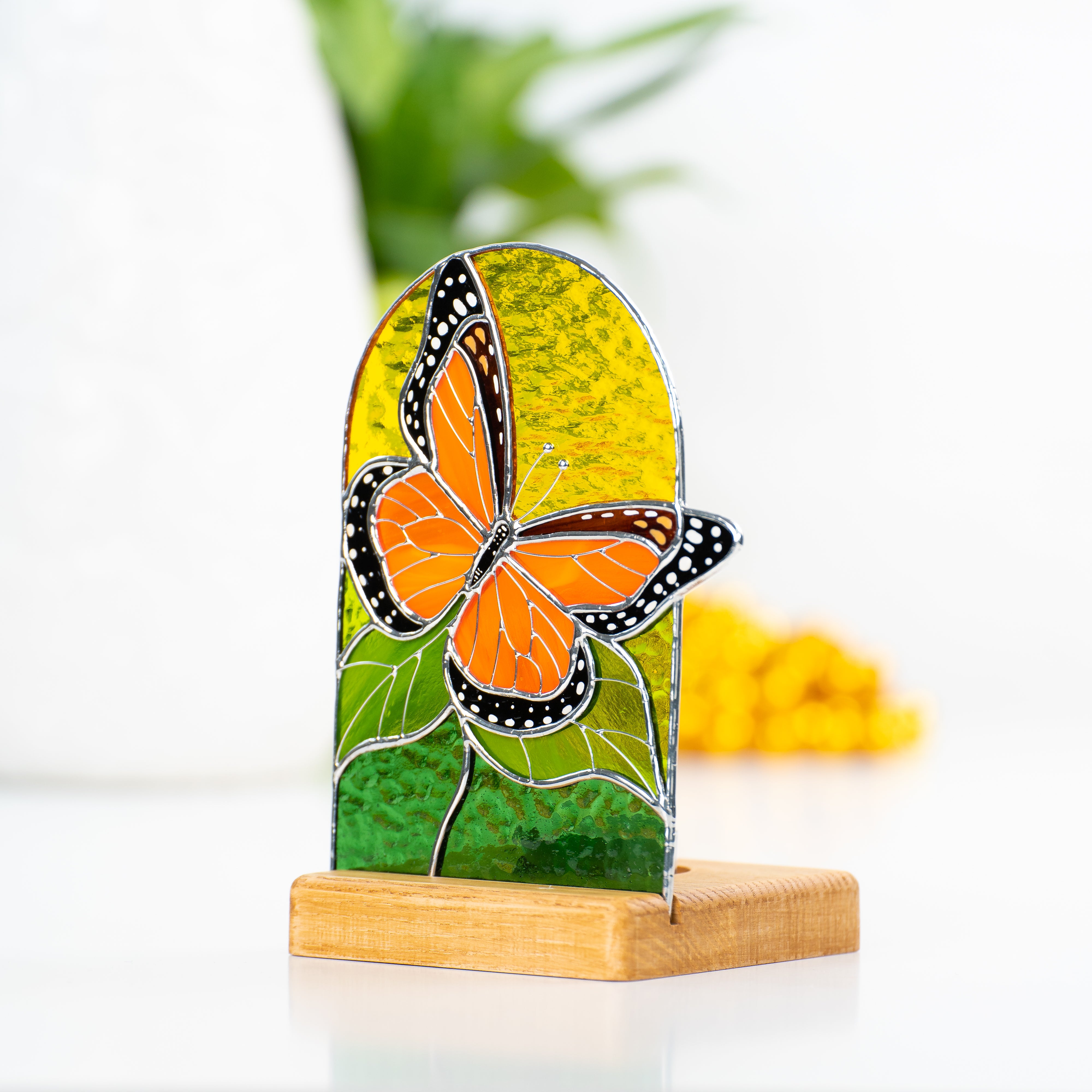 Panel in a wooden base with the candle behind depicting monarch butterfly of stained glass