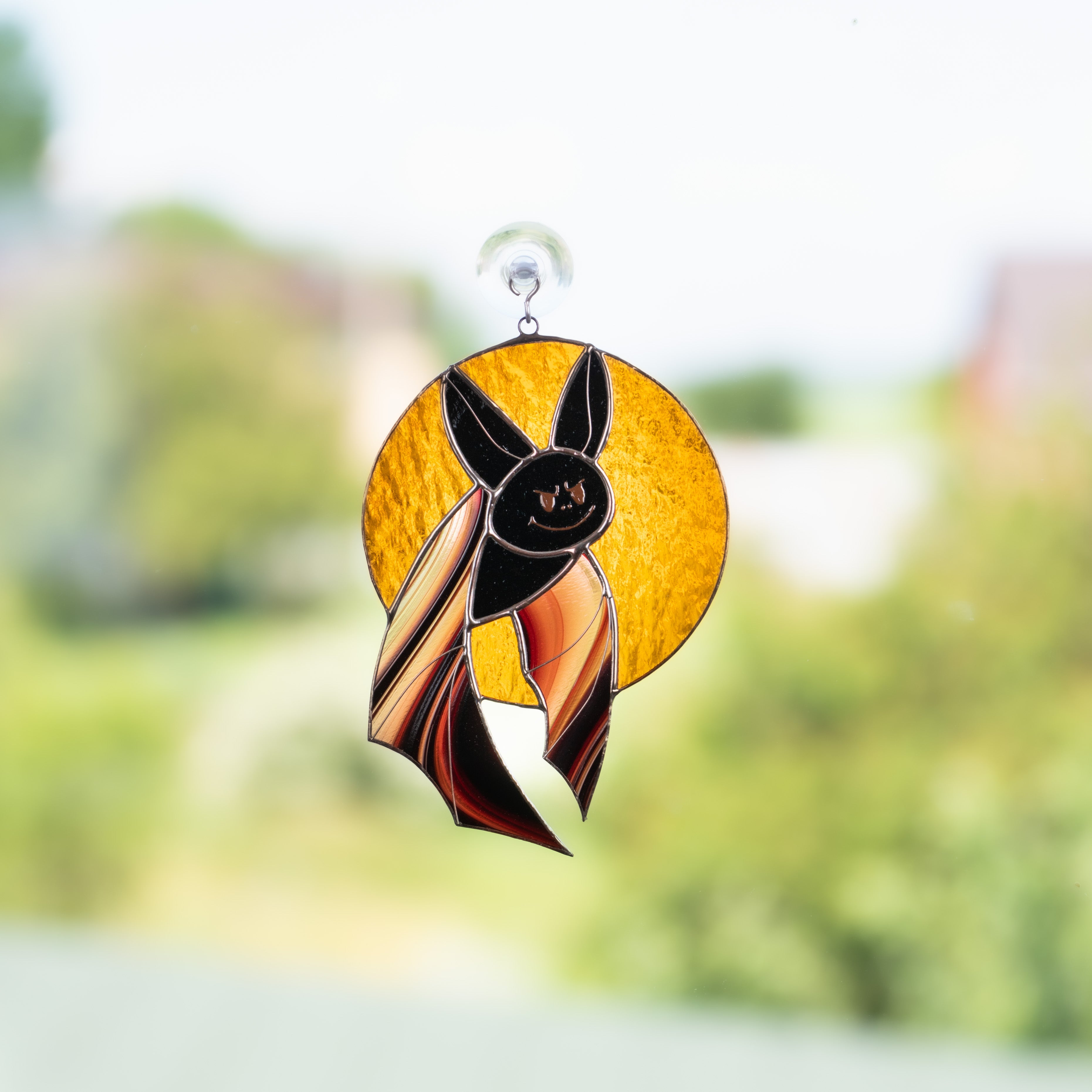 Stained glass black bat with brown wings on orange moon suncatcher for Halloween