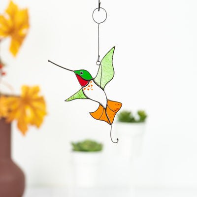 Stained glass suncatcher of hummingbird with green wings and orange tail
