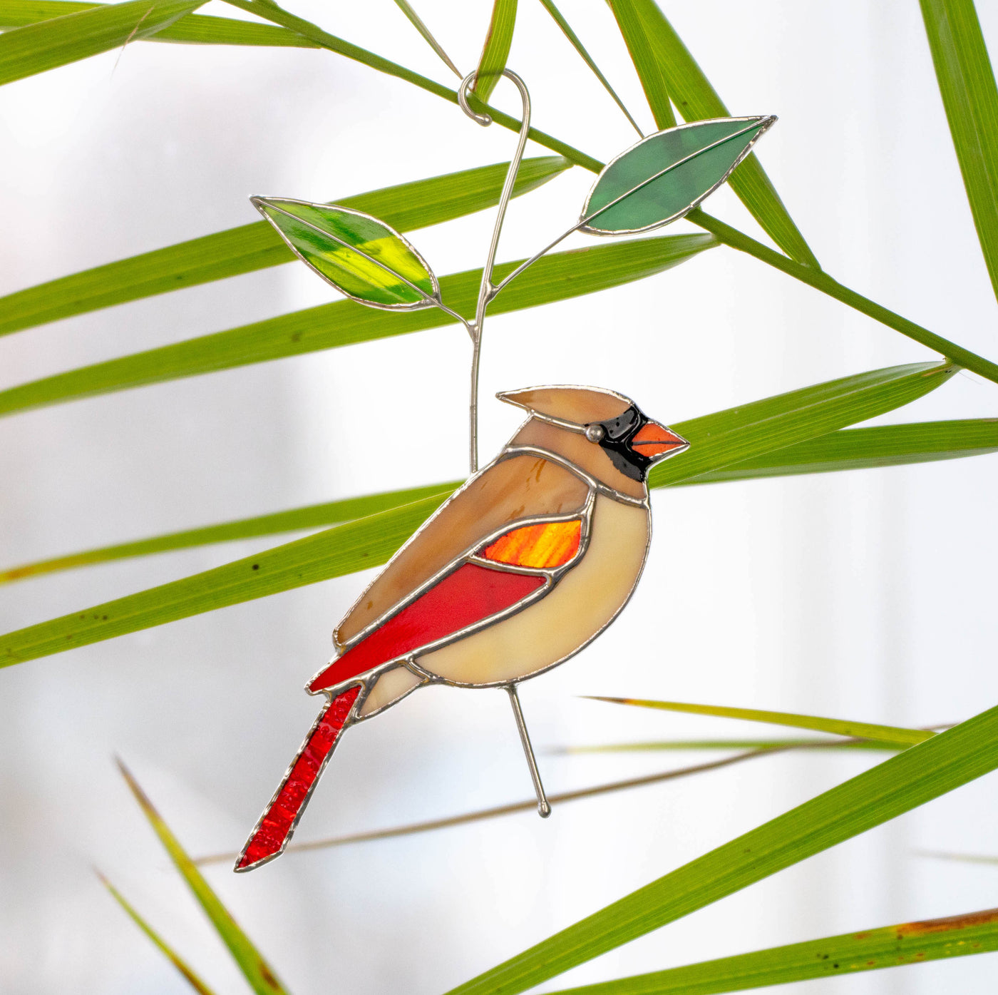 Stained glass female cardinal on the branch with leaves suncatcher