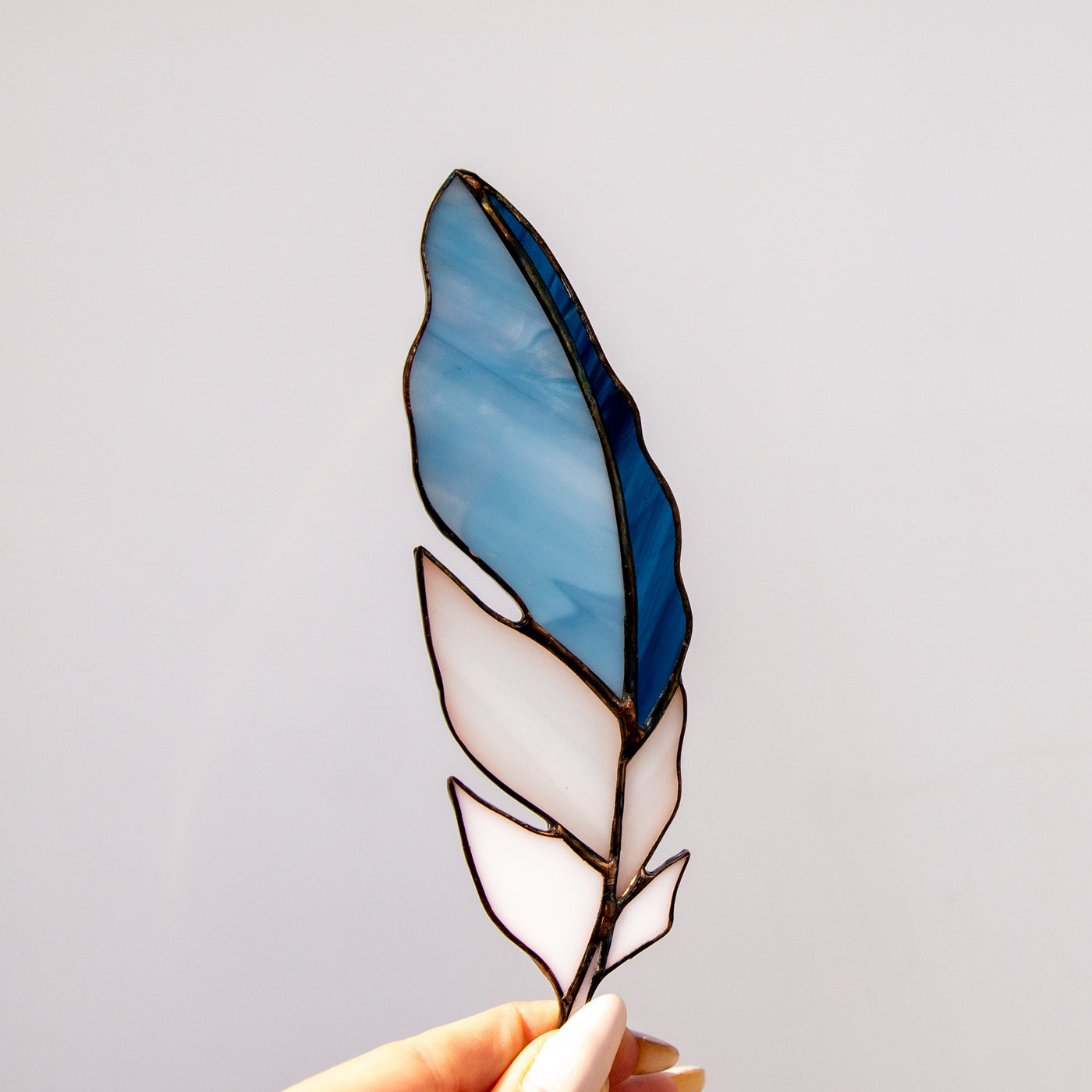 Stained glass sky-blue with white and navy parts feather window hanging