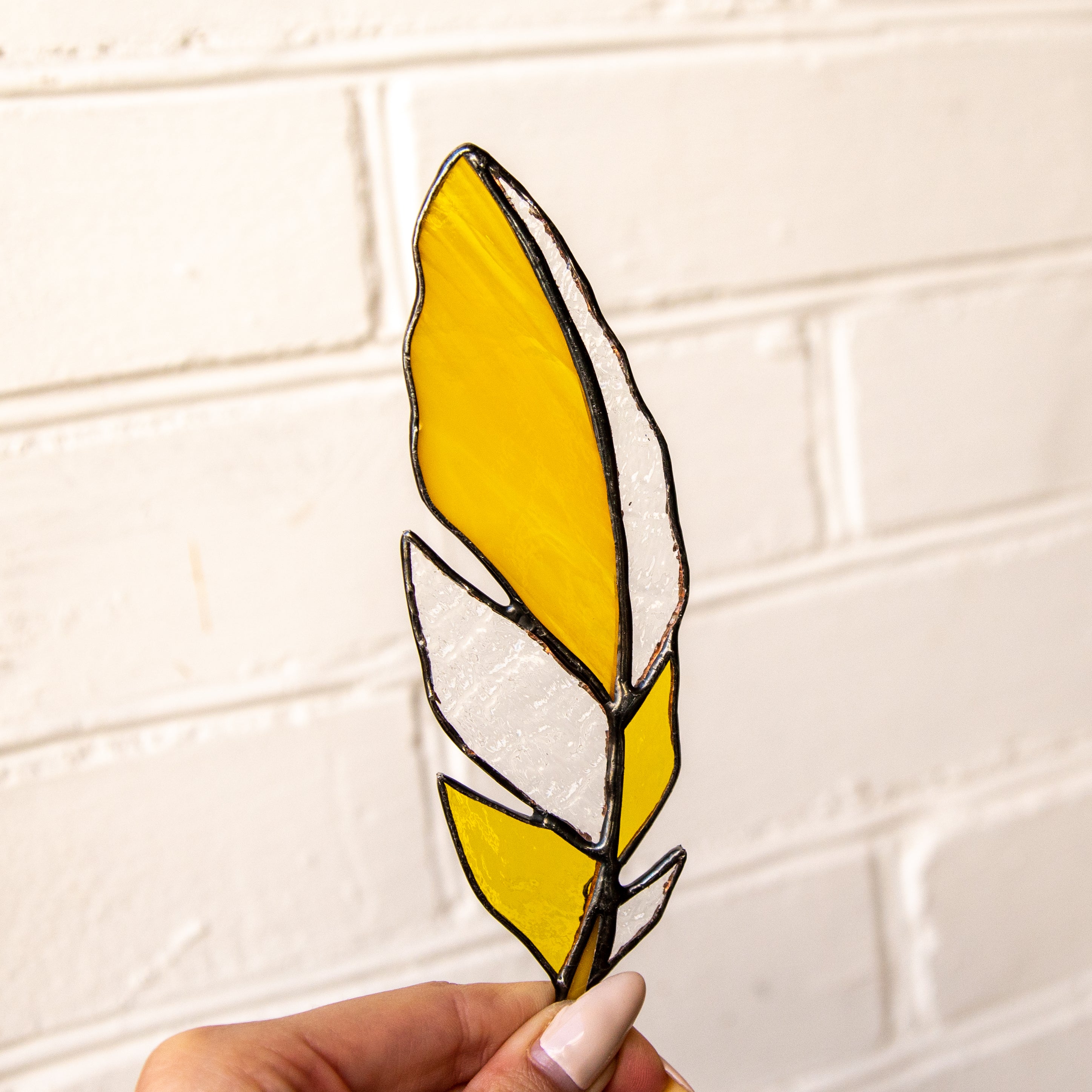 Suncatcher of a stained glass yellow feather with clear parts
