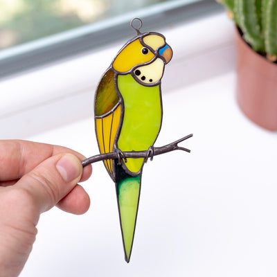 Sitting on the branch green parakeet suncatcher of stained glass