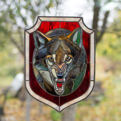 Stained glass grey wolf portrait in an oval with red background window hanging 