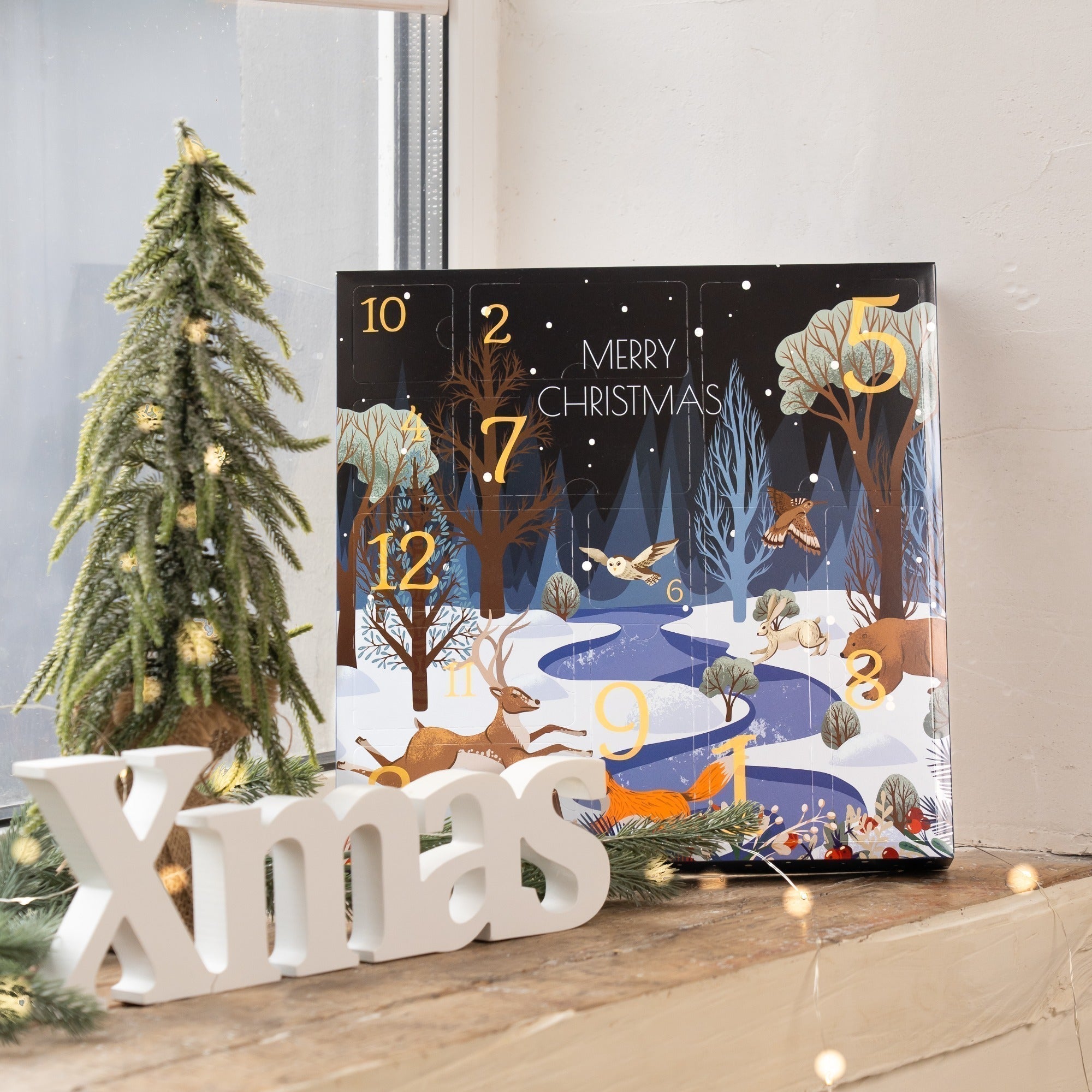Advent calendar with Christmas scene design, white 'Xmas' letters, and decorated tree.
