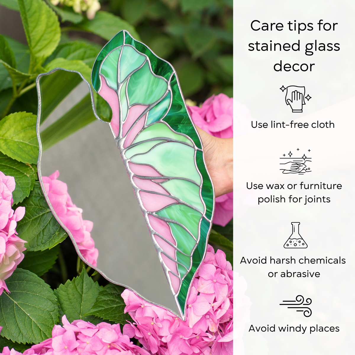 Caladium Leaf Stained Glass Mirror held among pink hydrangeas - care for this handmade stained glass decor with a lint-free cloth, wax the solder joints, avoid harsh chemicals and windy places