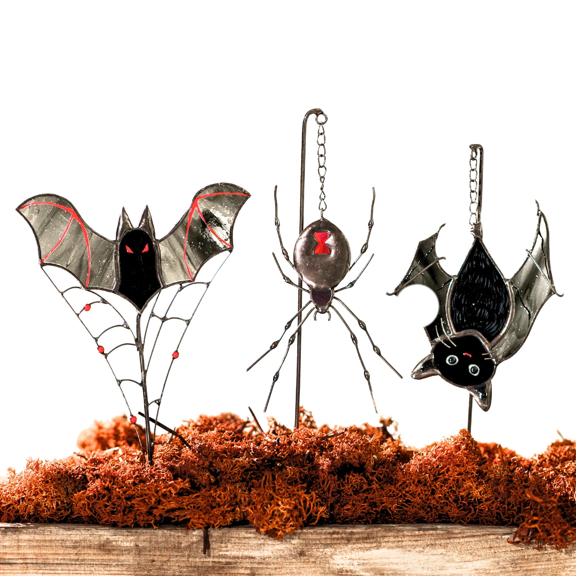 Set of three Halloween stained glass plant stakes on a white background - vampire bat on a beaded wire web, black widow spider and an upside-down cat-bat with green eyes
