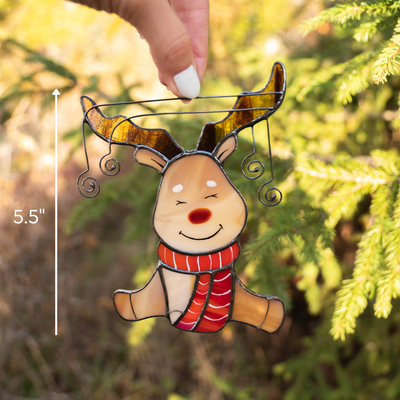 Reindeer suncatcher in sunlight, with scale measurement and pine background.