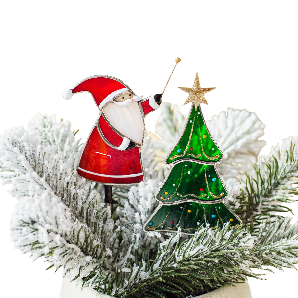 Santa with Christmas tree stained glass plant stakes in frosted fir branches - Santa with a magic wand beside a green glass tree topped with a gold star, handmade Christmas plant decor