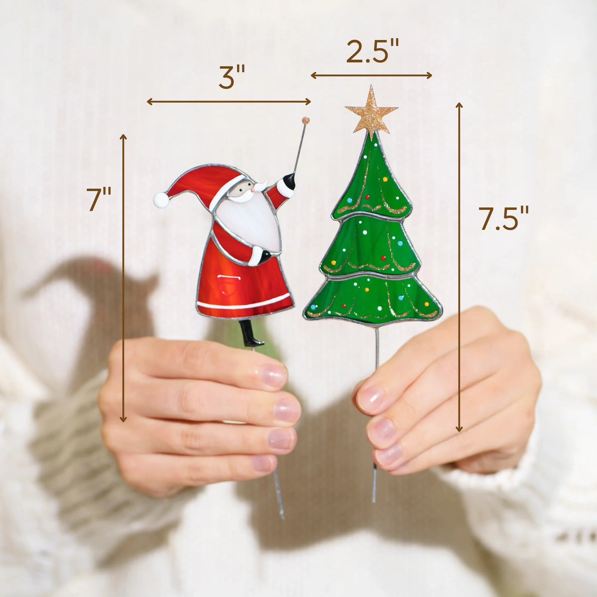 Hands holding the Santa and Christmas tree stained glass plant stakes - Santa 7 inches tall and 3 inches wide, Christmas tree 7.5 inches tall and 2.5 inches wide - handmade Christmas decor