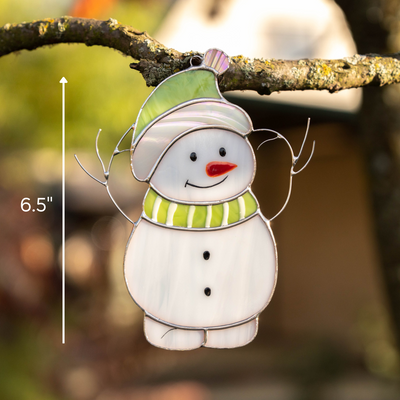 Snowman ornament hanging outdoors from a branch, size labeled as 6.5 inches for reference in natural setting.