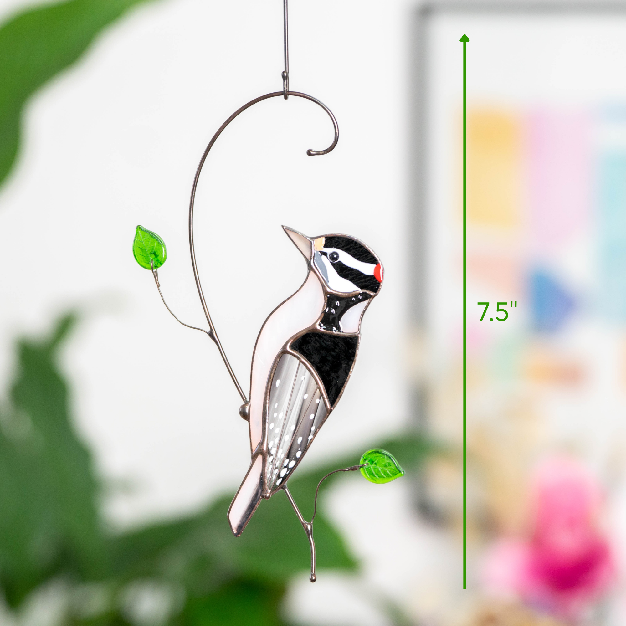 Full view of woodpecker suncatcher hanging with green leaves, size marked as 7.5"

