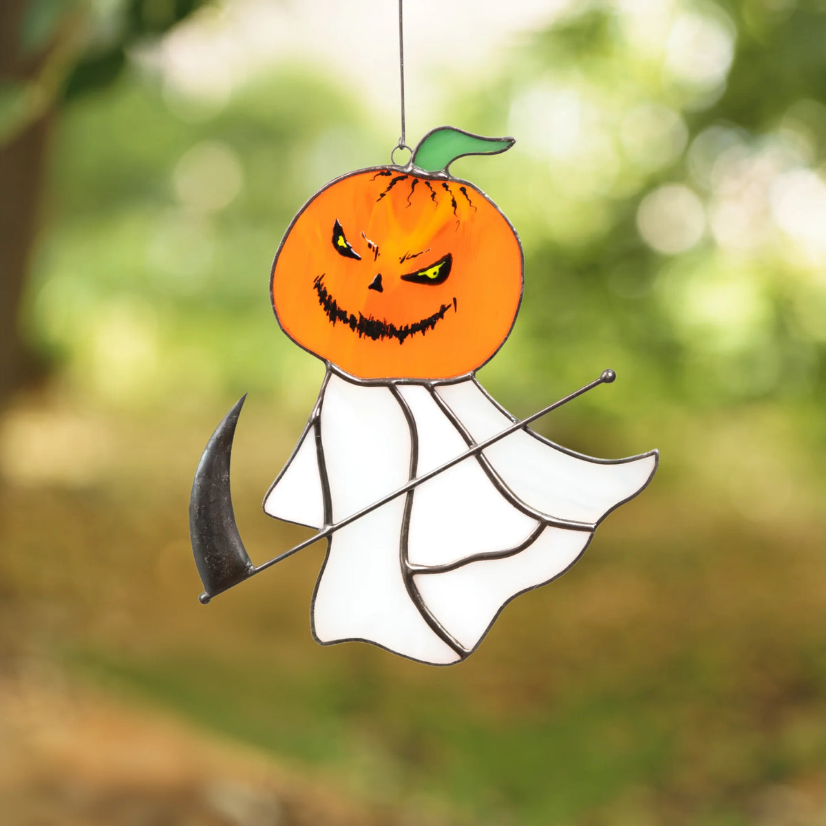 Grim reaper pumpkin head stained glass suncatcher measuring 5 by 5.5 inches, shown on a Halloween-themed bat and pumpkin background.