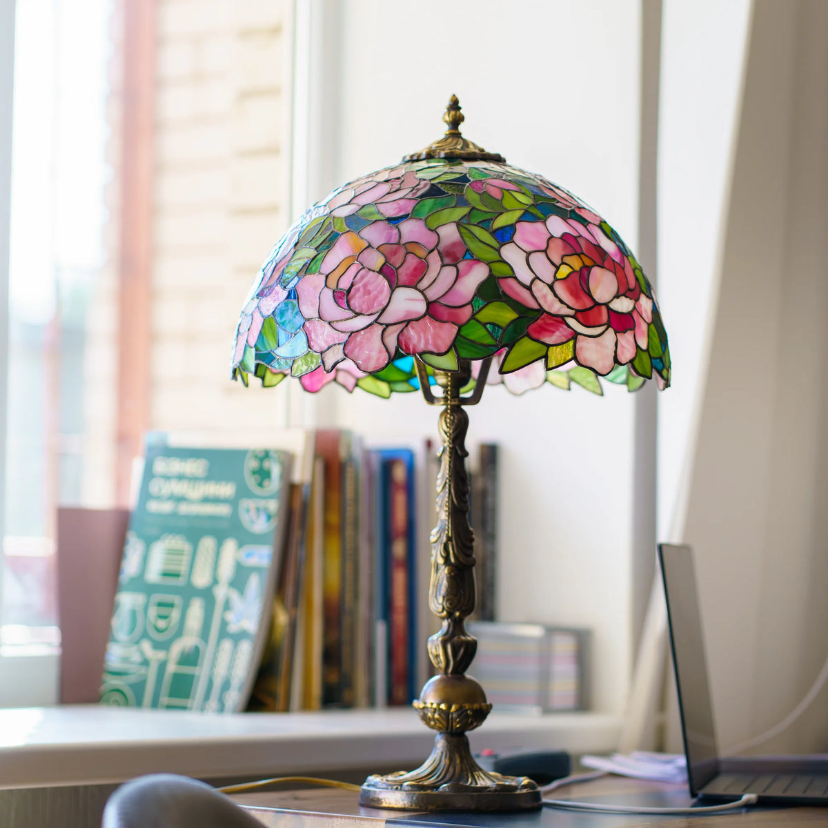 Stained glass peony table lamp displayed on a console table against striped wallpaper, with a framed painting and gilded picture frames nearby - handmade Tiffany lamp for elegant home decor