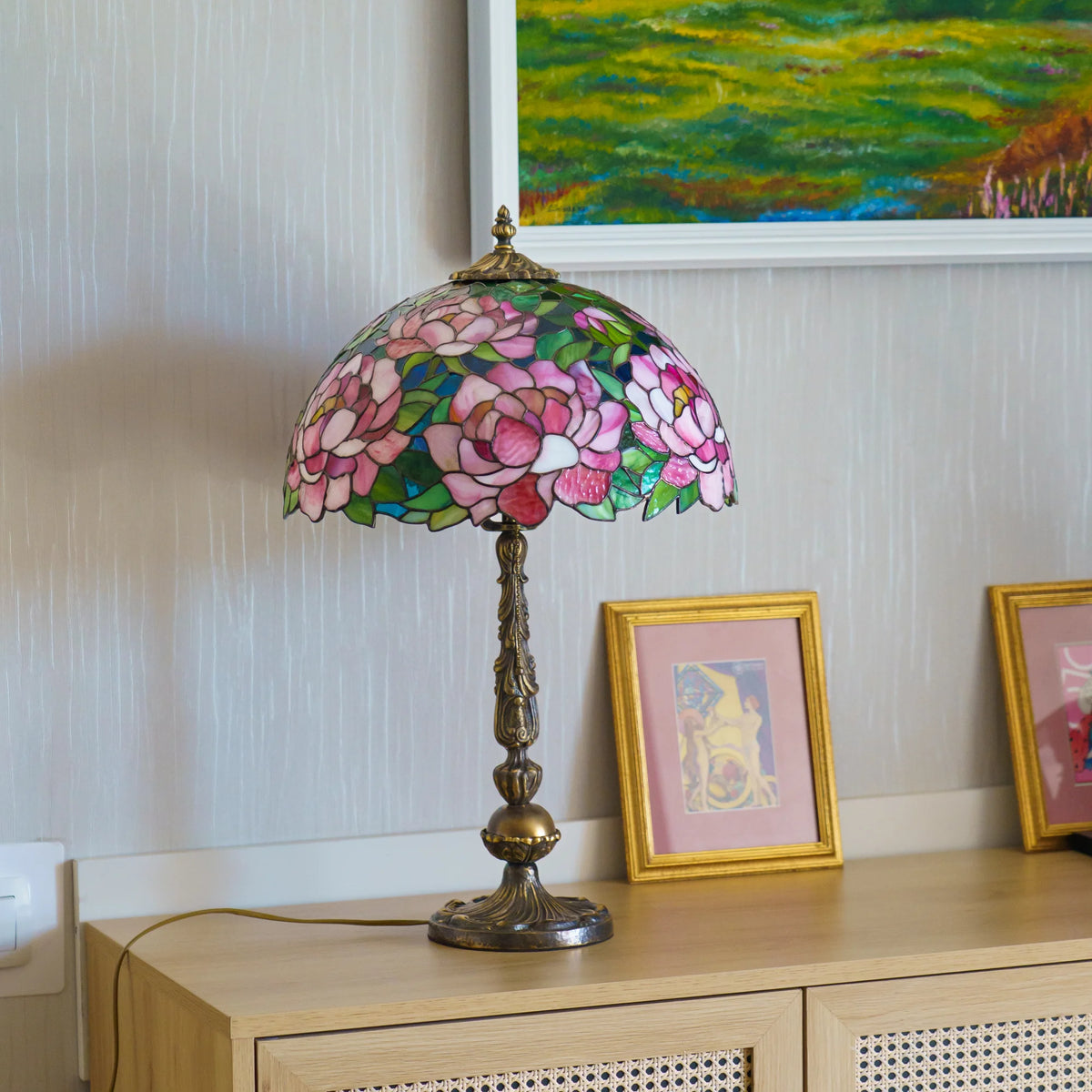 Handmade stained glass peony table lamp on a white background, full view showing the pink and green glass dome shade on an ornate brass base with pull chain - Tiffany style stained glass lighting