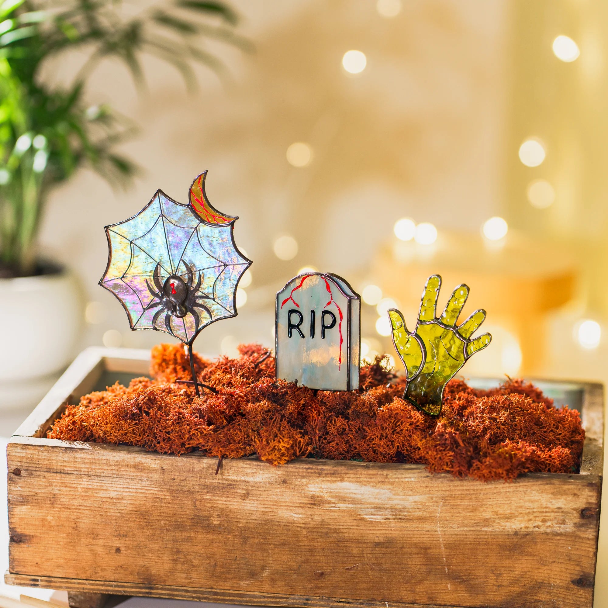 A set of Halloween stained glass decorations inside a wooden planter against a soft, bright background, perfect as a festive present.