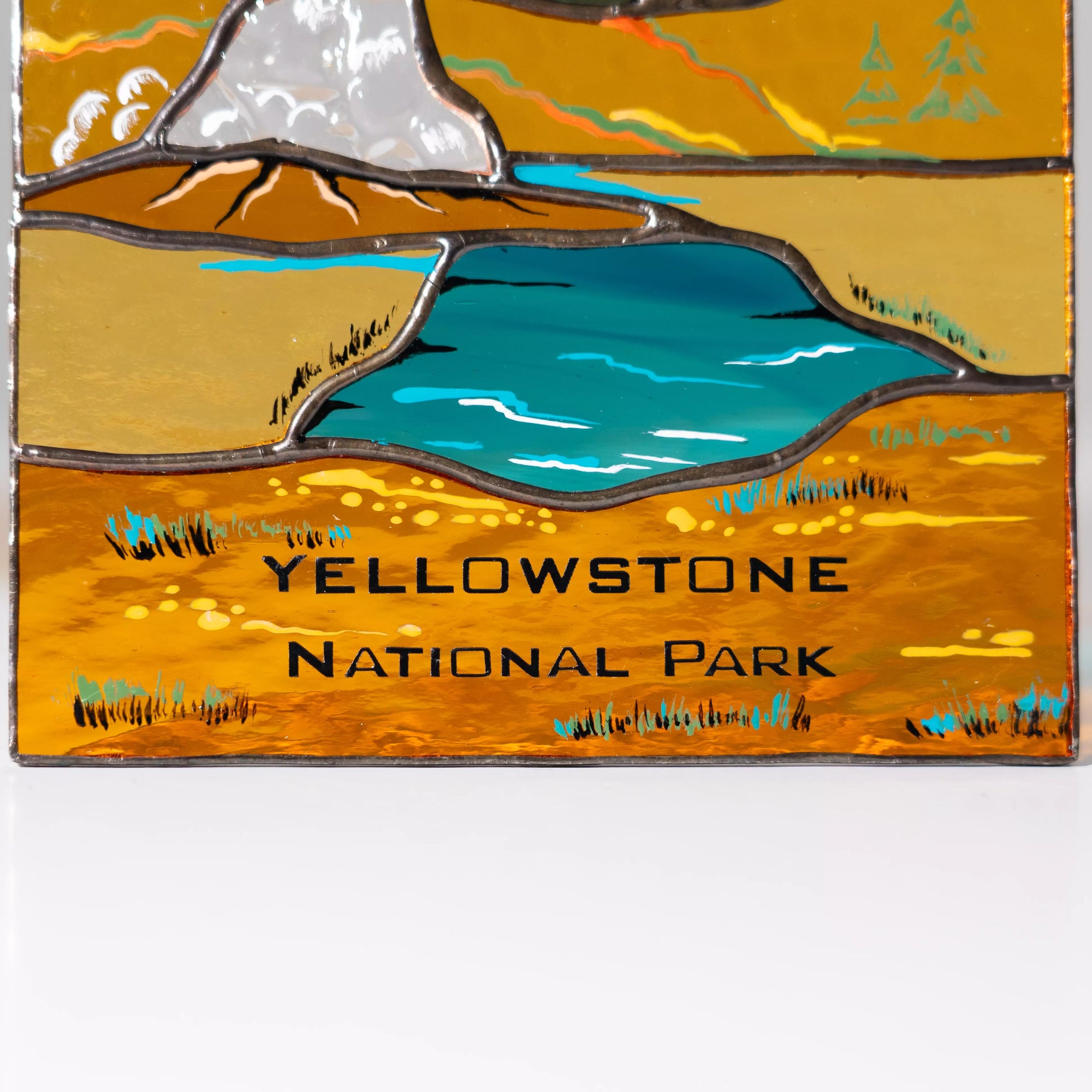 Decorative plaque with a stylized illustration of Yellowstone National Park featuring a lake and mountains.