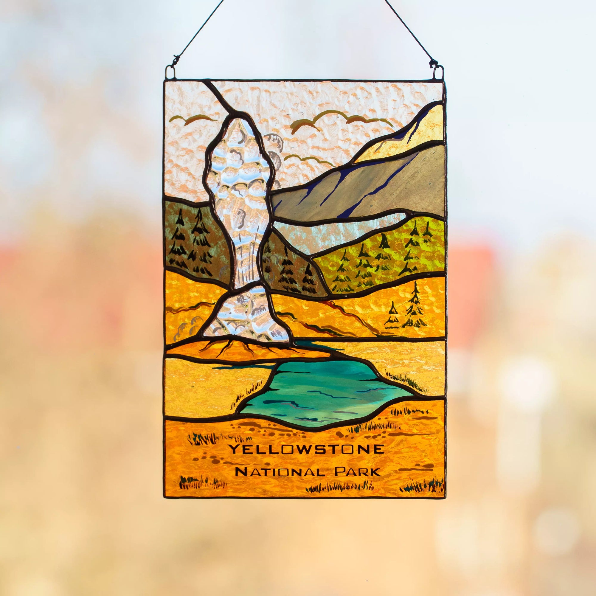Stained glass panel of Yellowstone National Park with mountains and lake.
