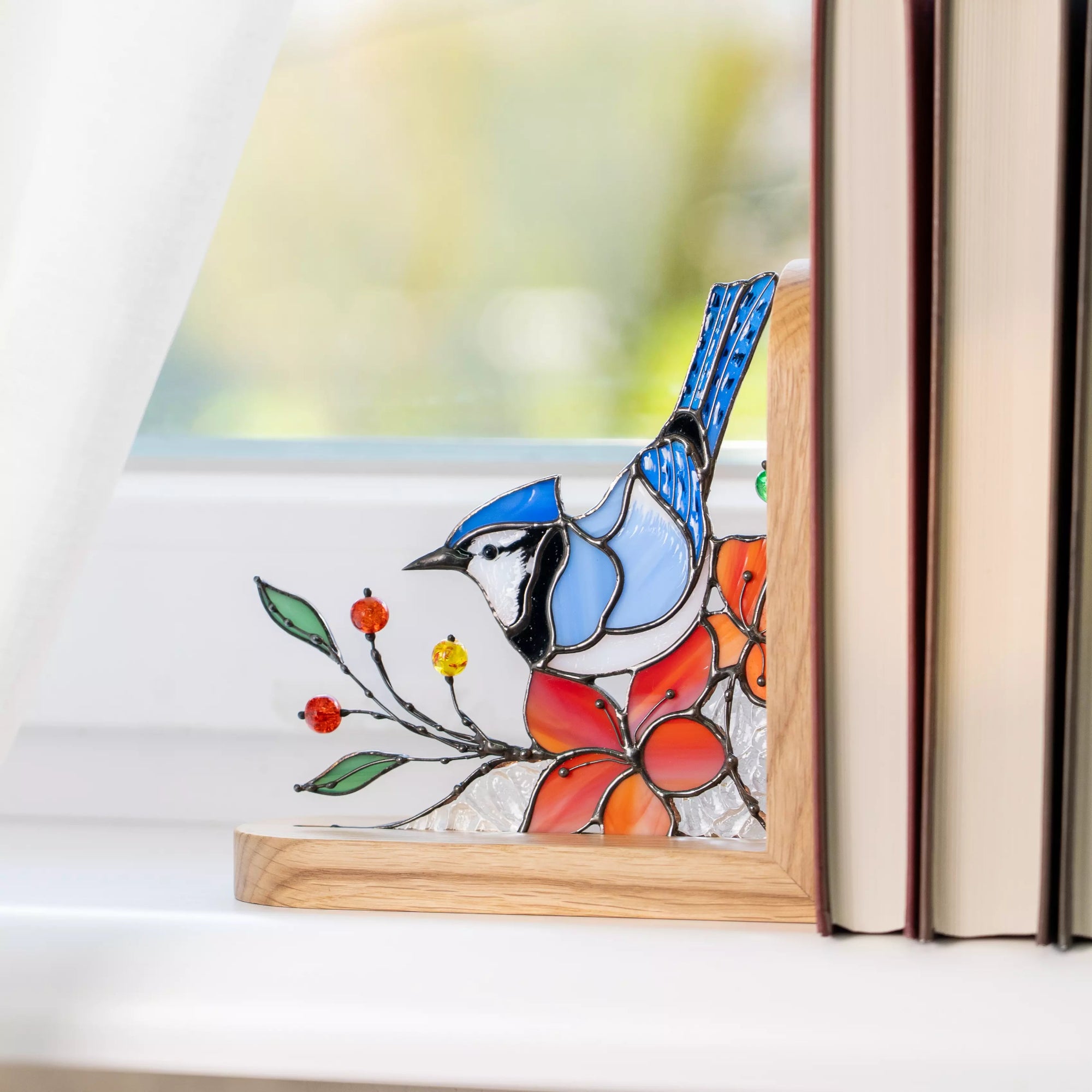 Side view of a blue jay stained glass bookend holding books upright.