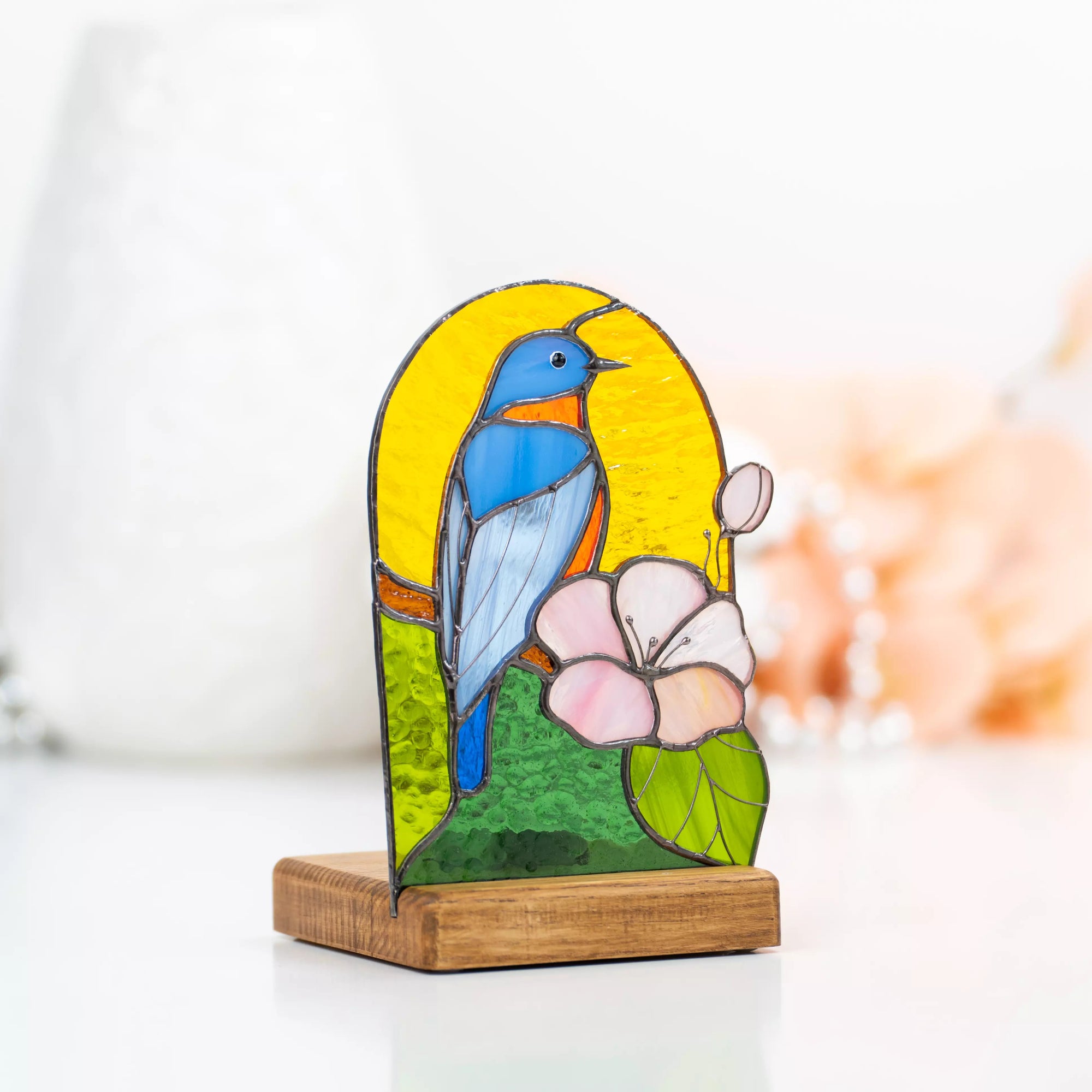 Side view of stained glass lamp with tealight, bluebird and flower on yellow and green glass