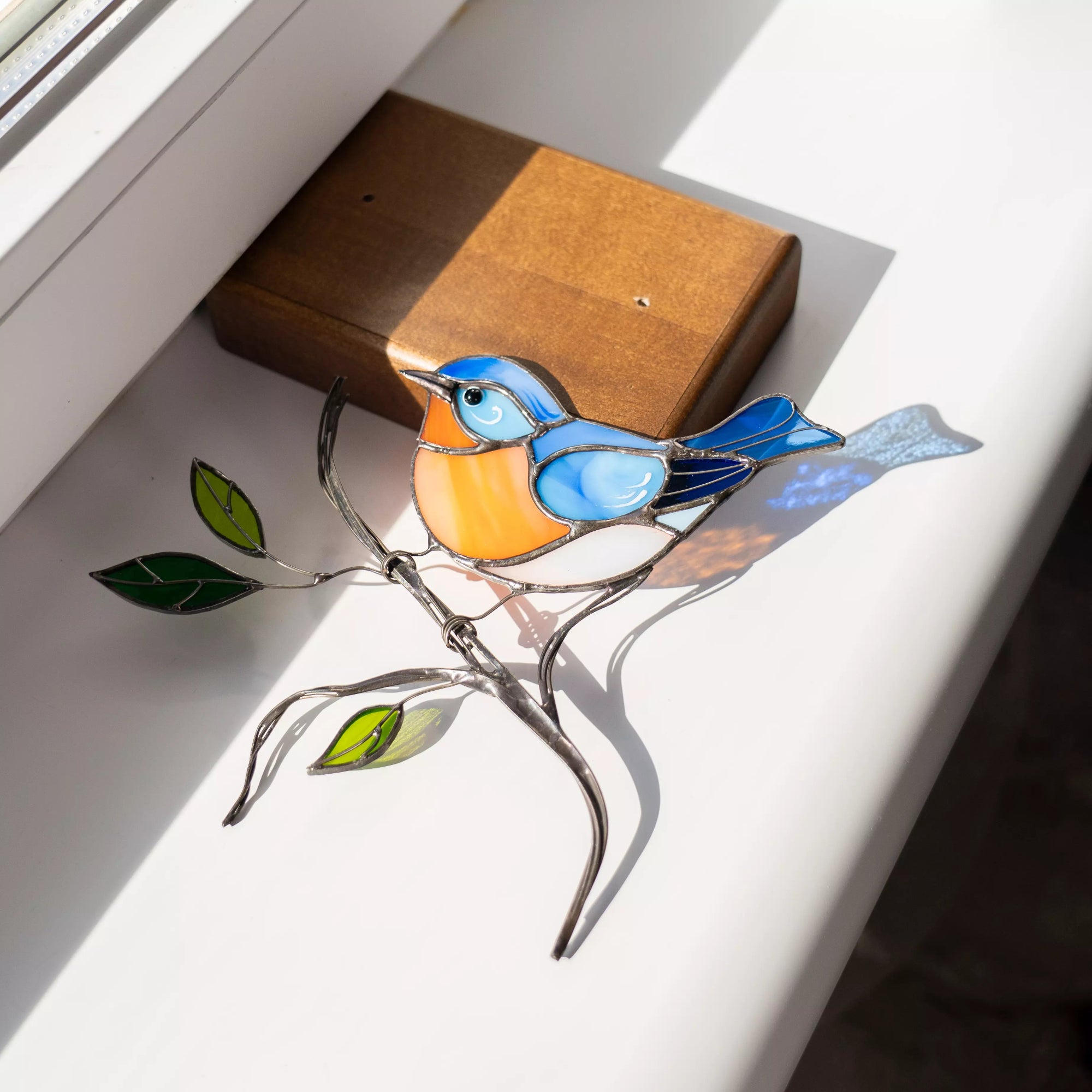 Side angle of stained glass bluebird with outstretched wing and color details on wooden base