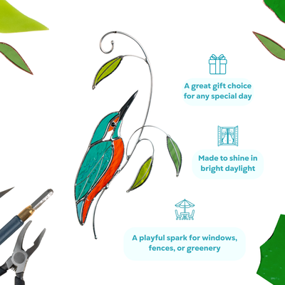 Stained glass kingfisher with turquoise wings and orange belly, perched on a branch near glass leaves.