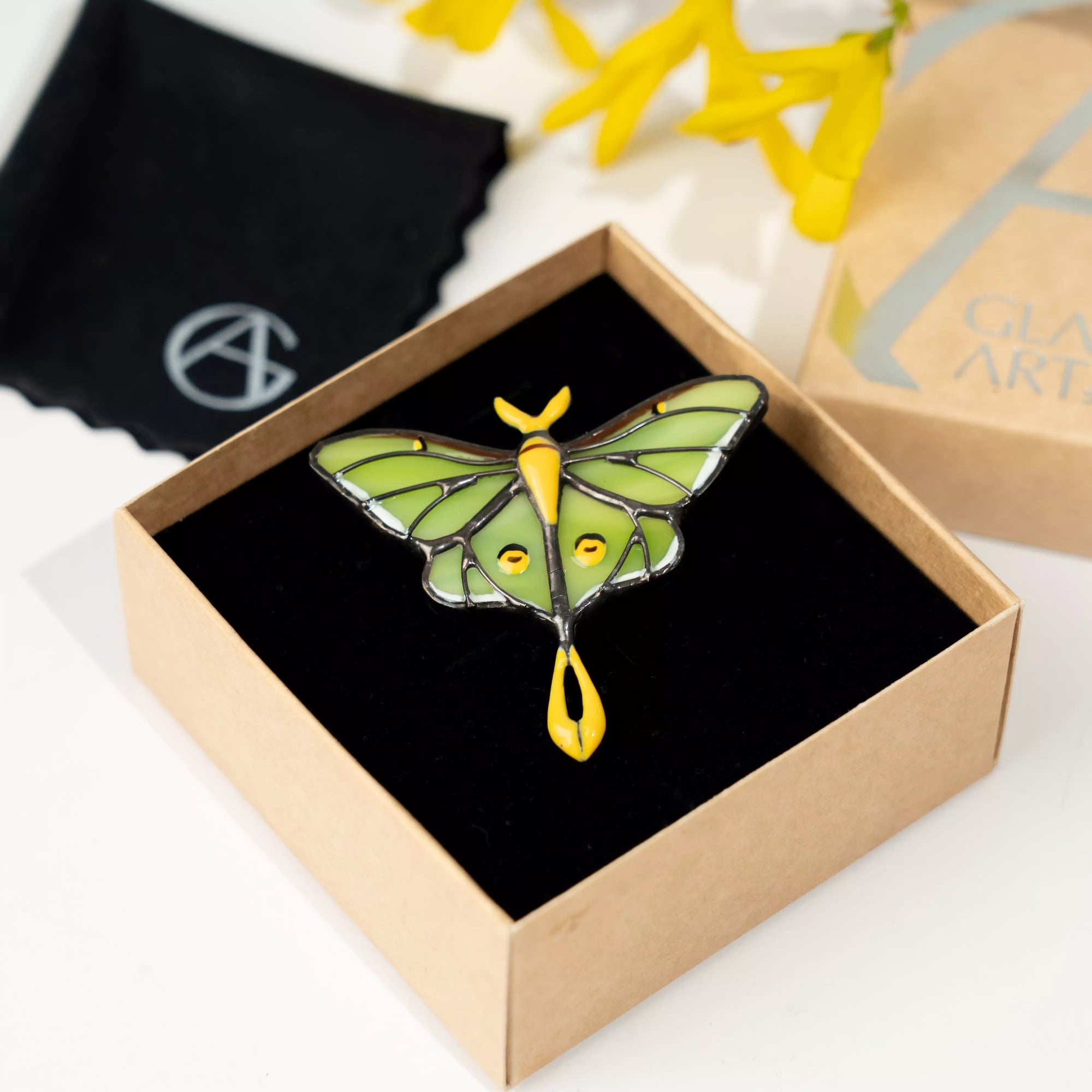 Butterfly luna moth stained glass brooch in a box with a brand logo in the background