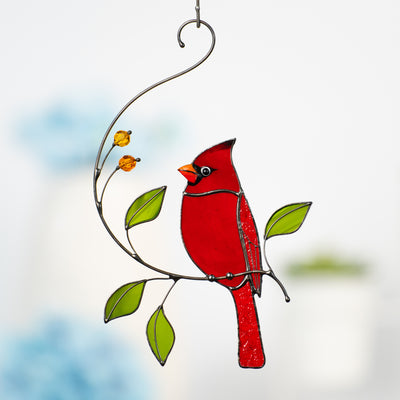 Handcrafted red cardinal suncatcher with smooth stained glass, orange glass beads, and green leaf details on swirling wire